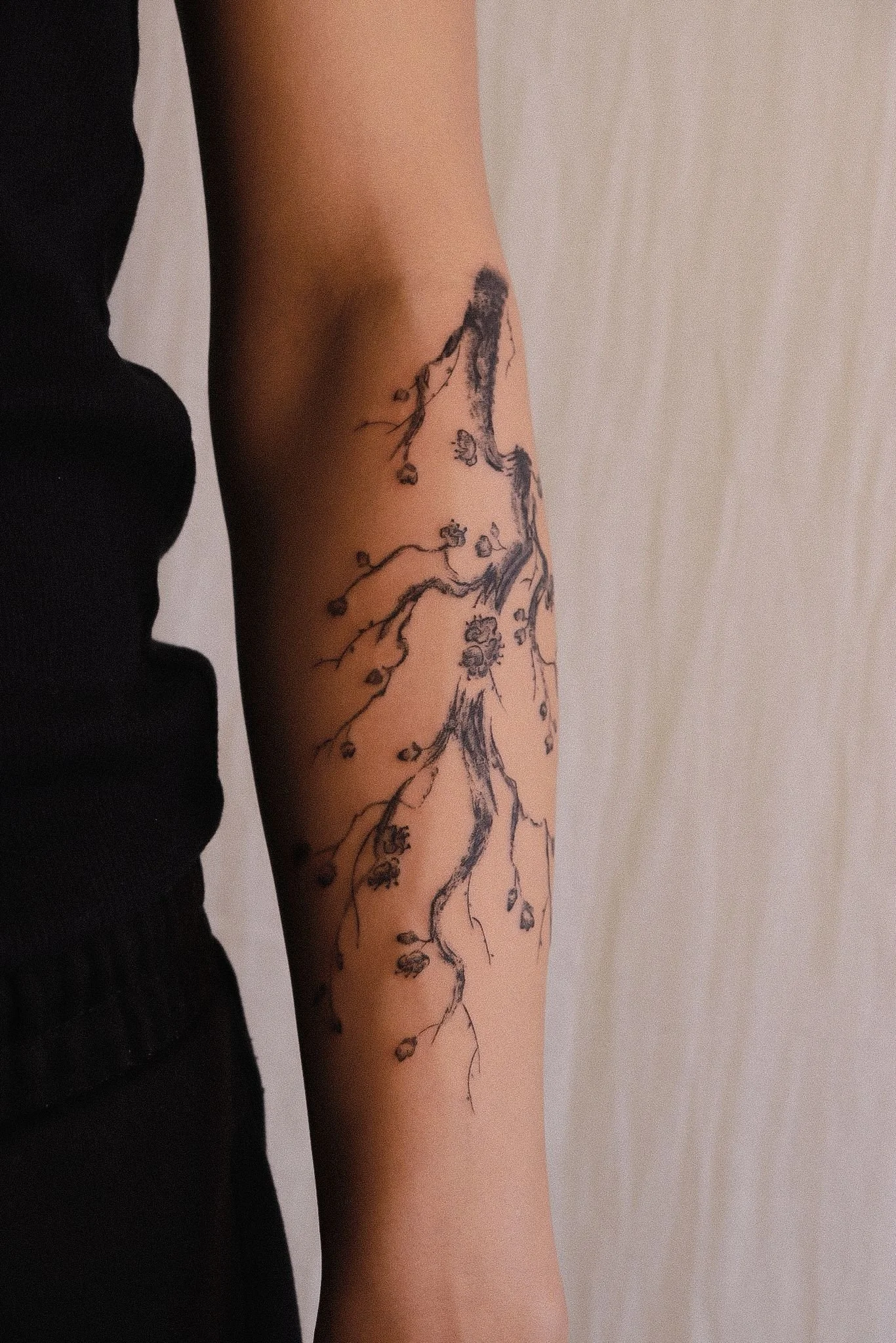 A person's arm with a tattoo of a tree in black ink.