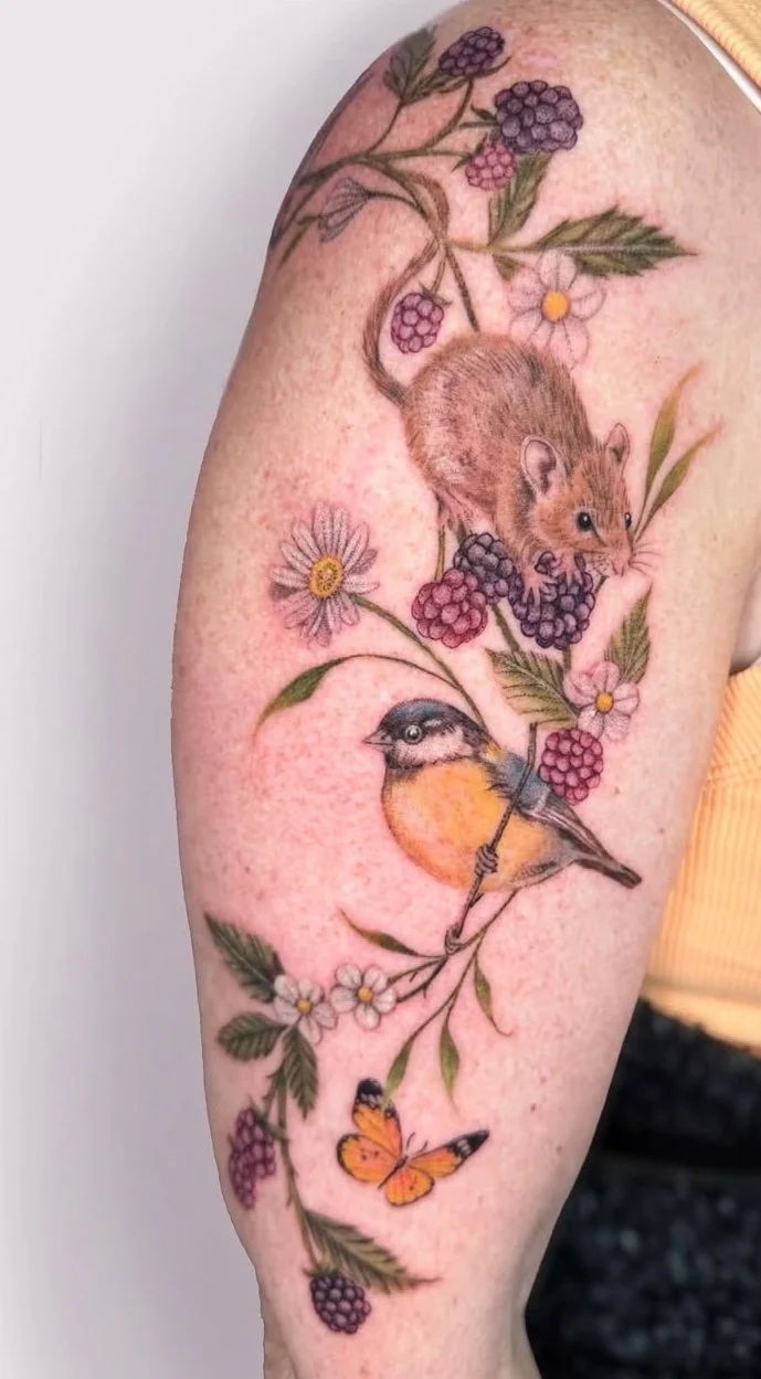 Colour nature tattoo of a harvest mouse on blackberries, a blue tit and an orange butterfly by guest artist Devin Evans