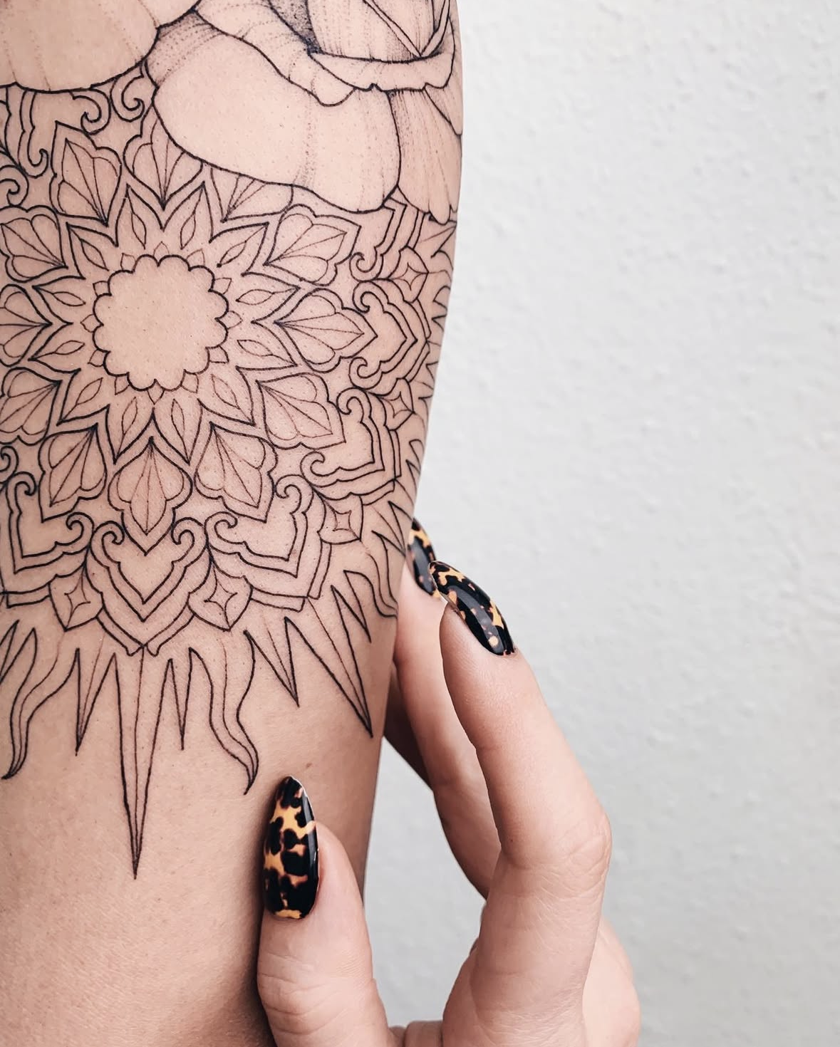 Fine line mandala tattoo with sun ray points beneath a dot work peony on the upper arm by @VERONICALILU