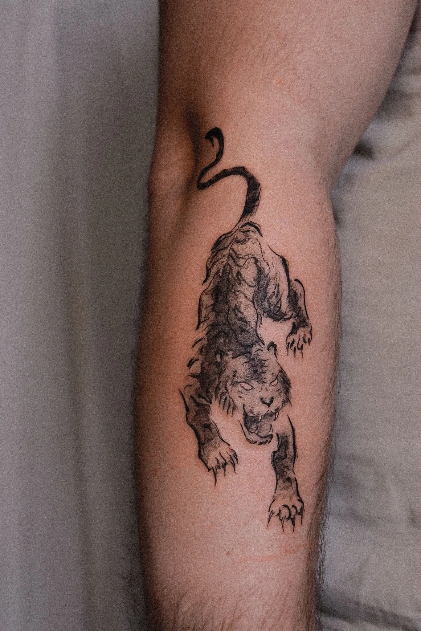 A tattoo of a lion and a flamingo on a person's forearm.