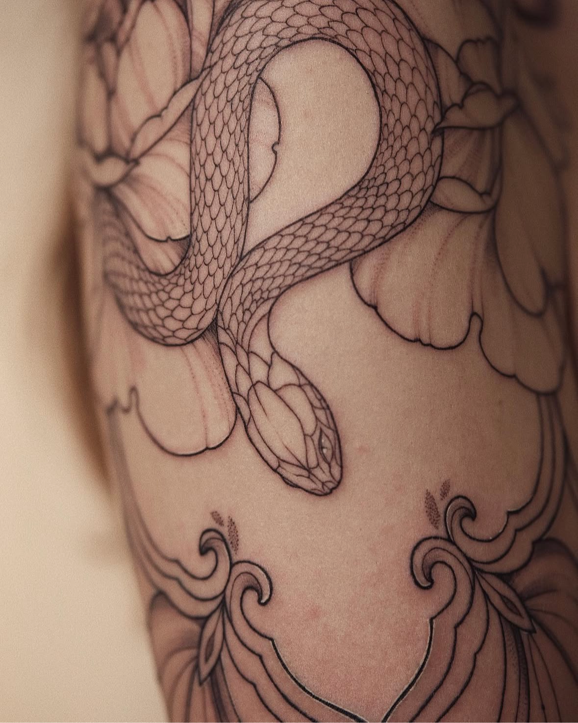 Close-up of a fine line snake tattoo with detailed scales coiled through peonies and ornamental scrolls @veronicalilu