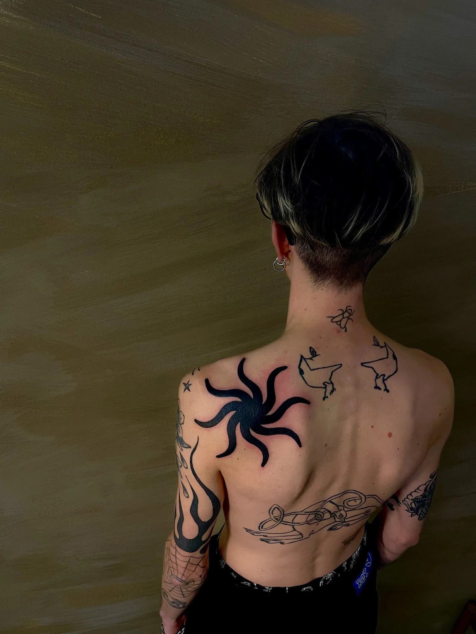 blackwork tattoo of a sun on the shoulder of a young man.