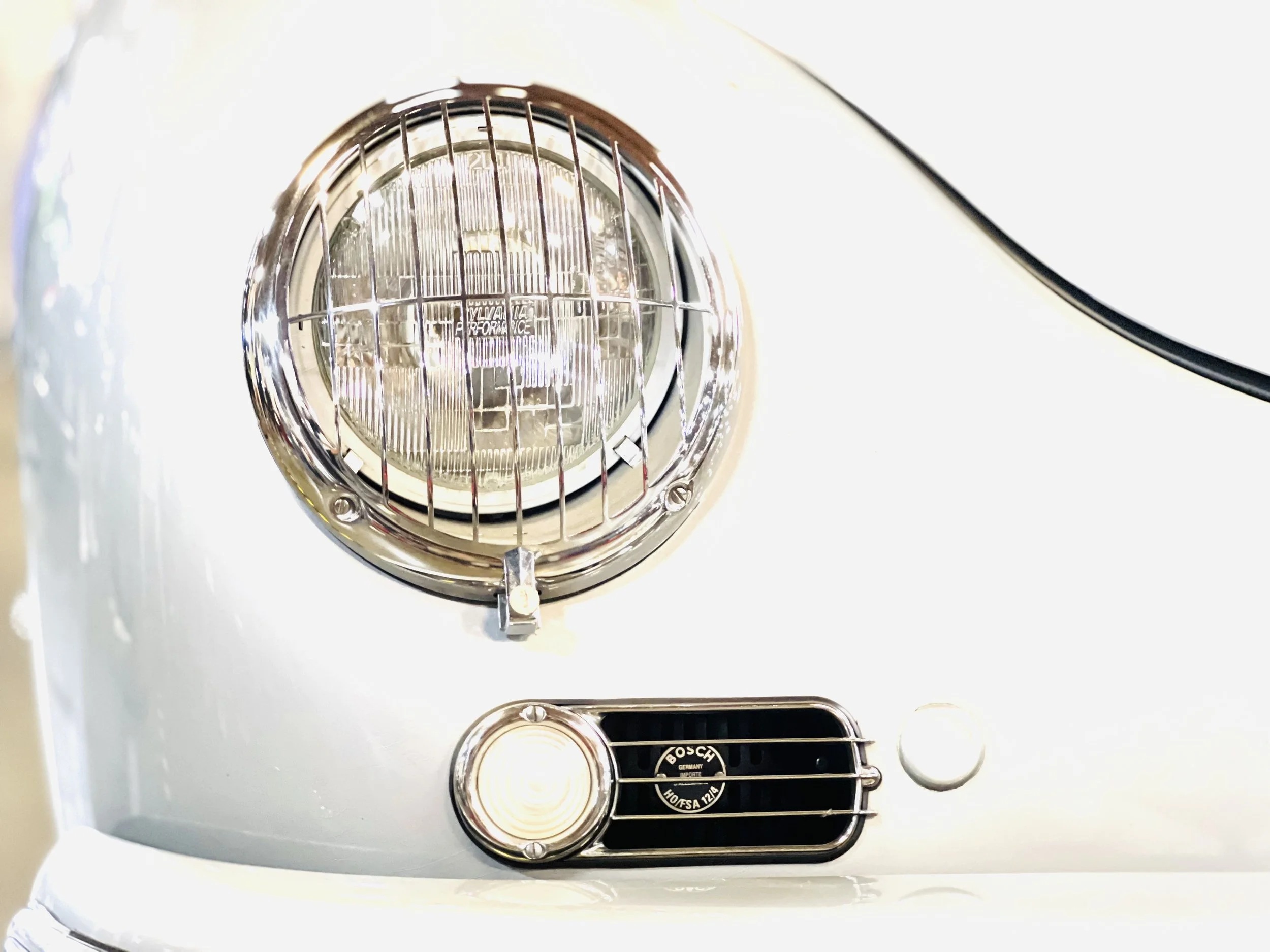 Close-up of a vintage car's headlight and grille, with chrome details and Bosch branding.