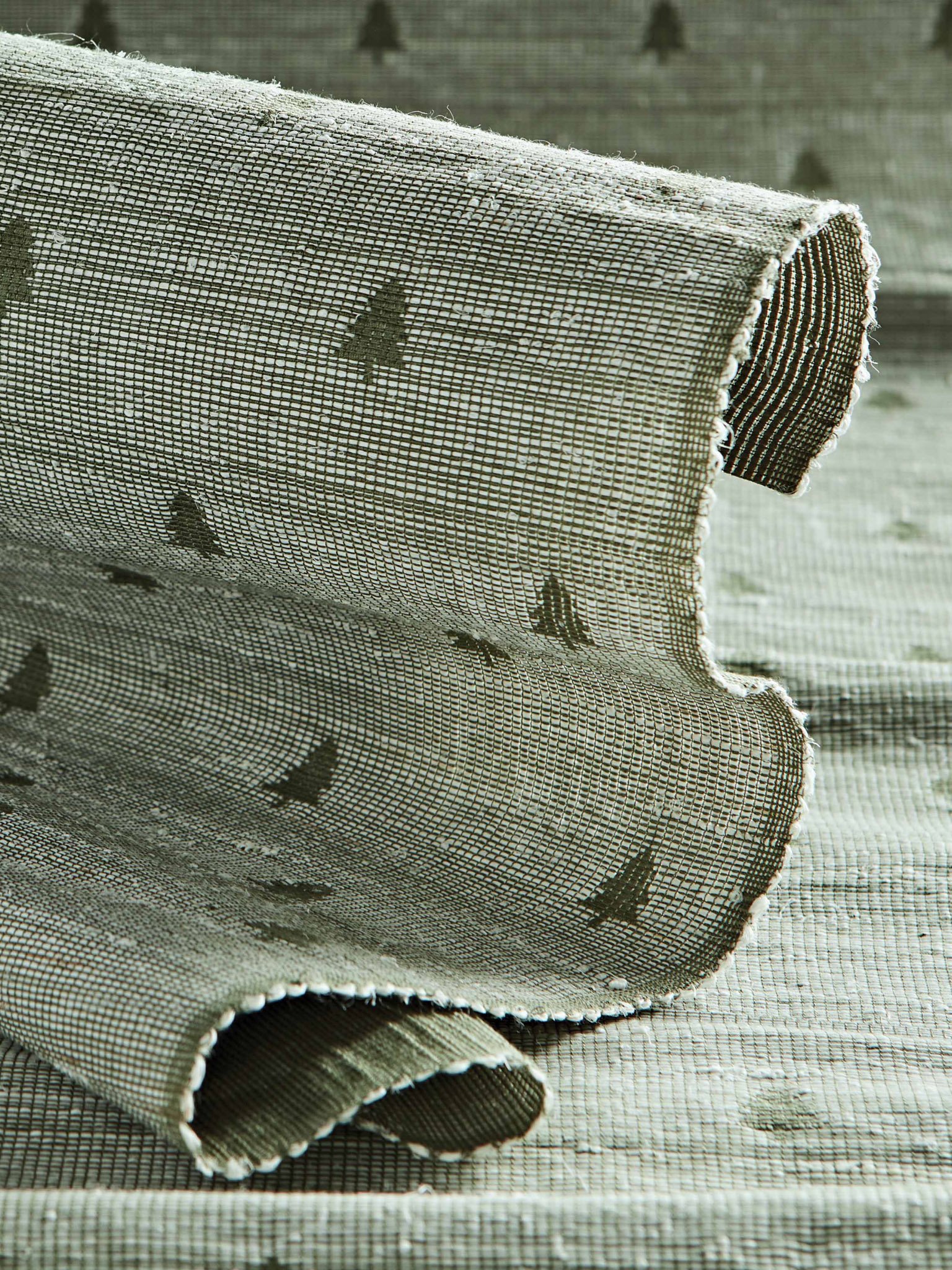 Rolled fabric with a textured pattern featuring small tree motifs.