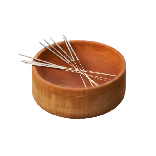A round wooden bowl with several acupuncture pins inside.