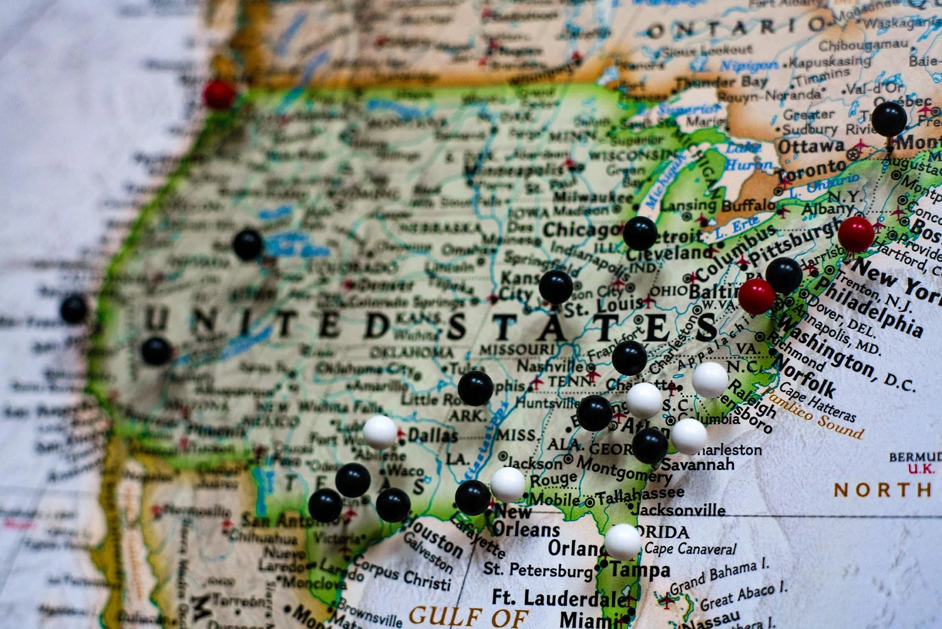 Close-up of a map of the United States with colored pins marking various cities.