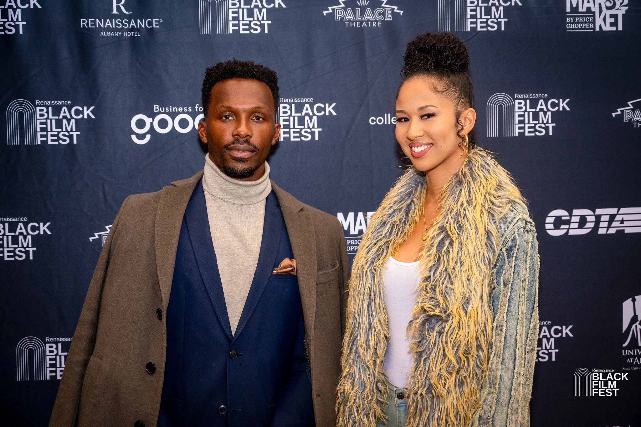 Two individuals posing on a red carpet at the Renaissance Black Film Fest, with a backdrop featuring festival logos and sponsors.