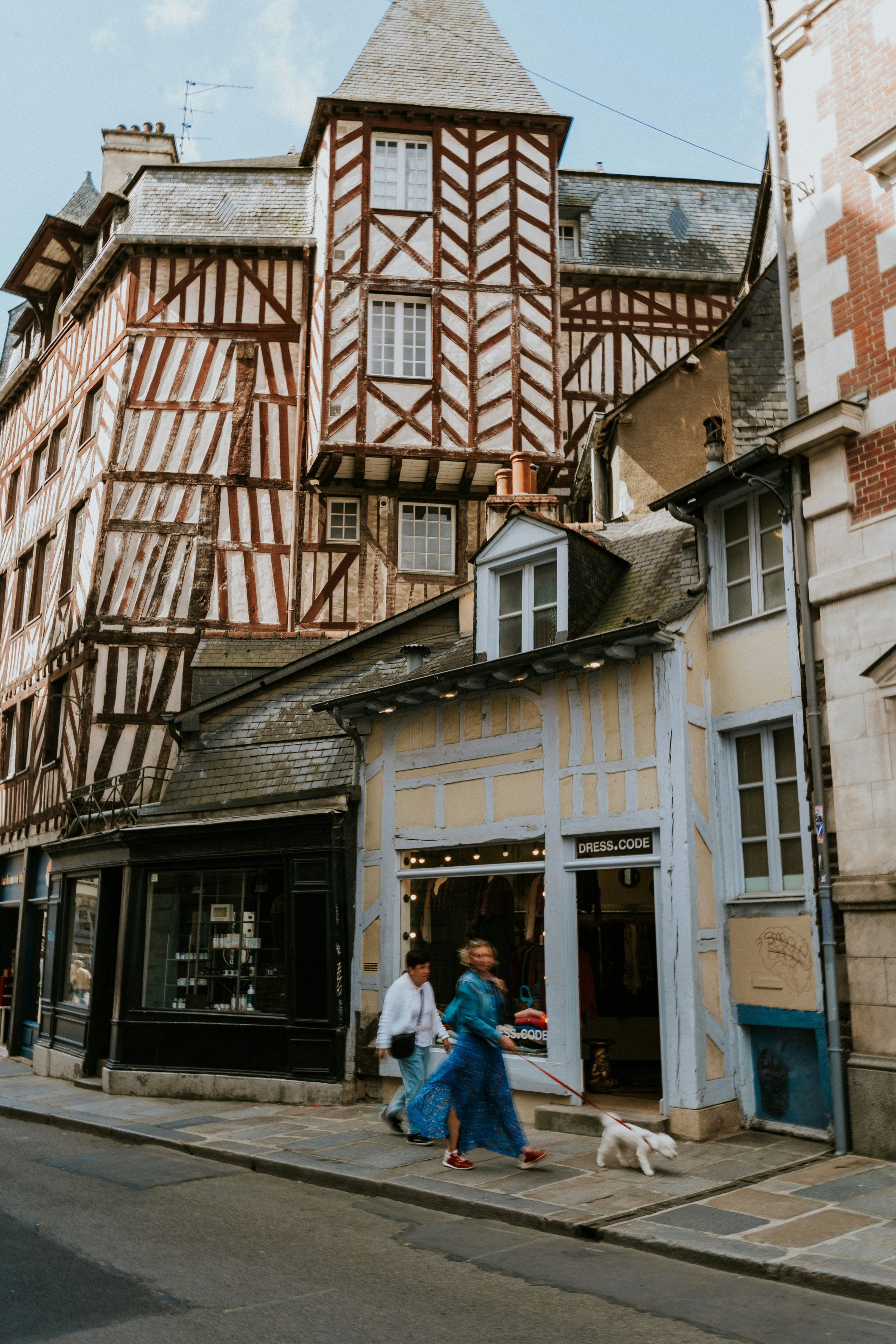 People walking on a cobblestone street in front of colorful, medieval-style buildings with timber framing. VOYA curates bespoke travel experiences in France and Napa Valley.