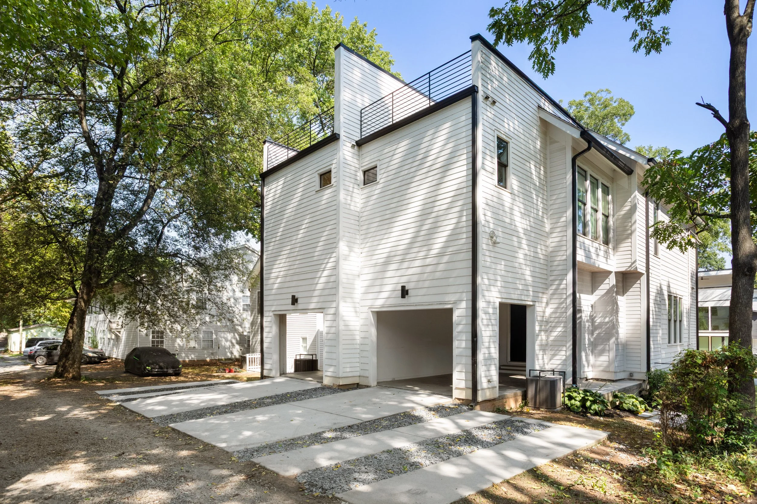 Modern white townhouse with rooftop terraces, attached garages, and tree-lined walkways