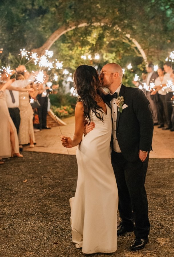Bride and groom kissing at night by the moongate