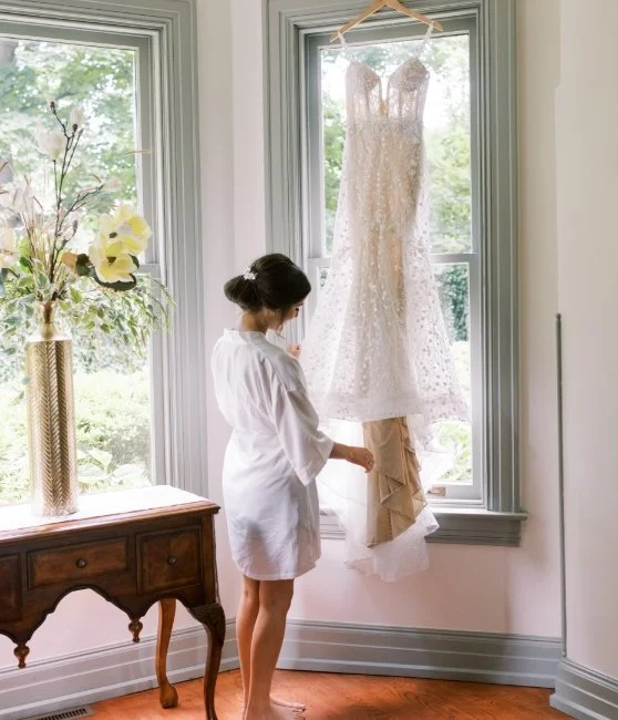 Bride looking at gown hanging in window