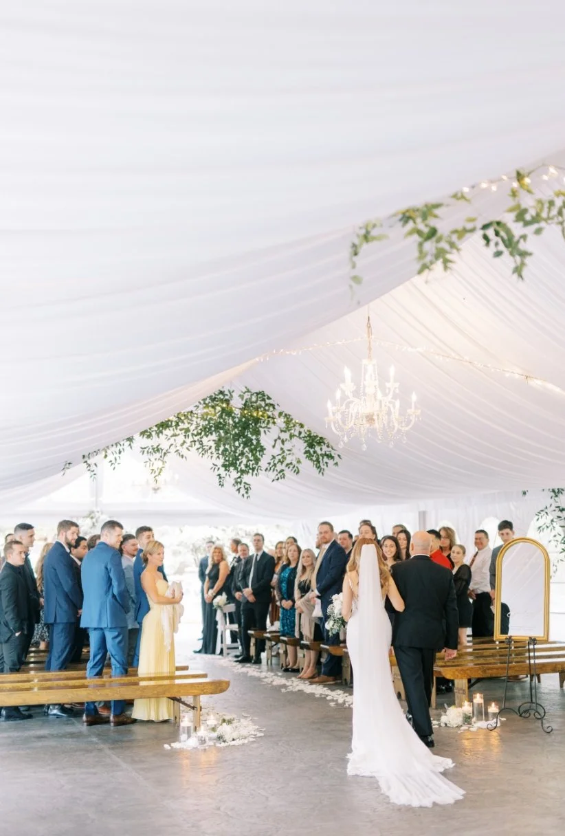 Bride walking down the aisle of the white wedding tent