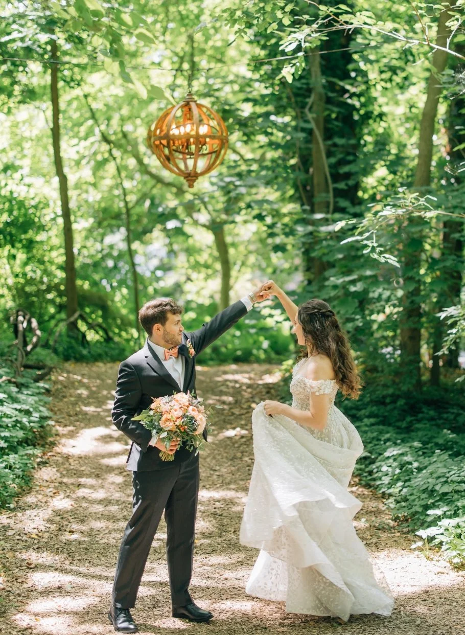 Wedding couple dancing in the woodlands under a globe chandelier