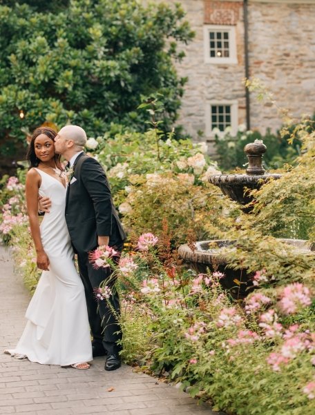 Groom kissing bride next to the beautiful fountain garden