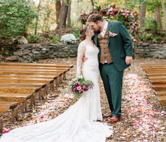 Couple kissing in petal covered outdoor woodlands