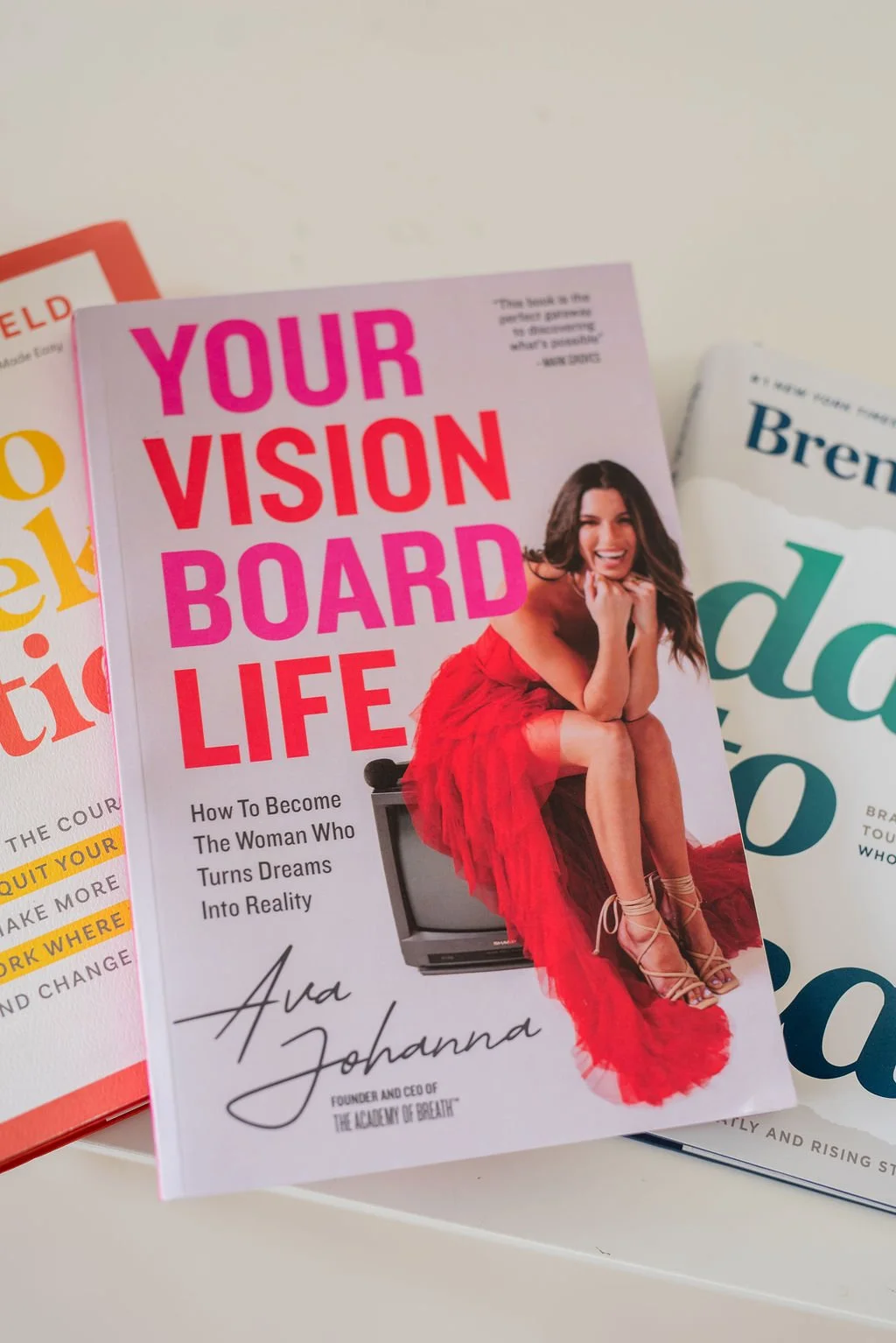 Your Vision Board Life book resting on a stack of personal development books