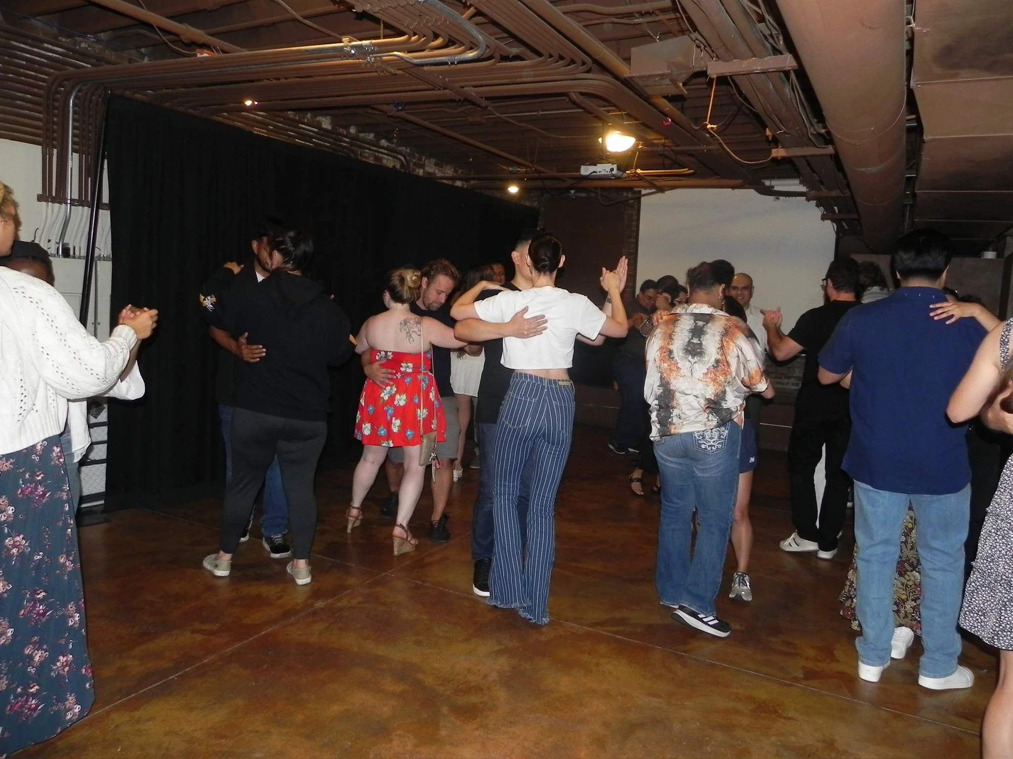 Group of people dancing tango together at a Salsa Kitchen event full of dancing salsa and bachata, taking classes of salsa and bachata, along with fun interactive games and prizes.