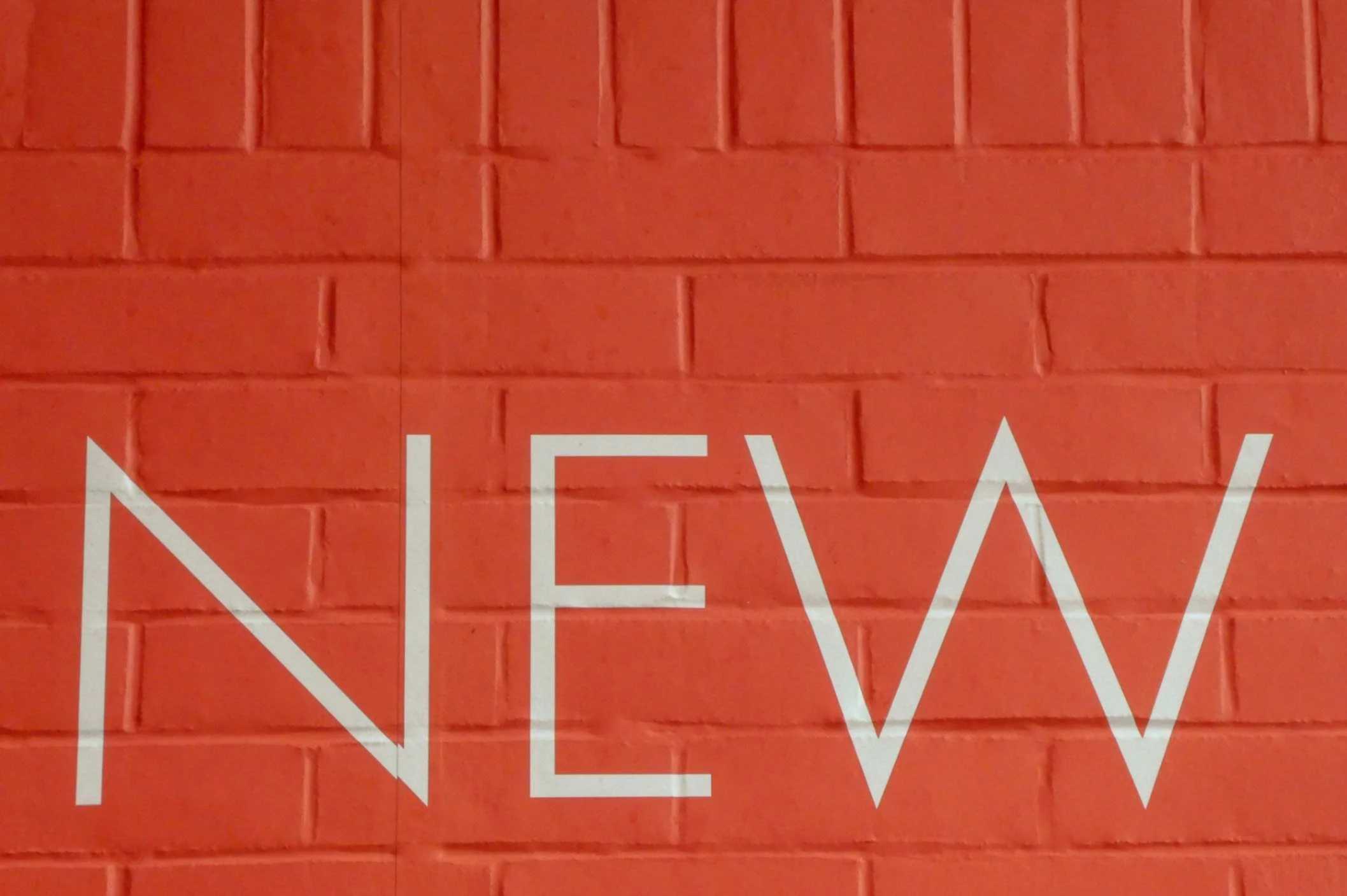 Red painted brick with the word NEW painted on top in white