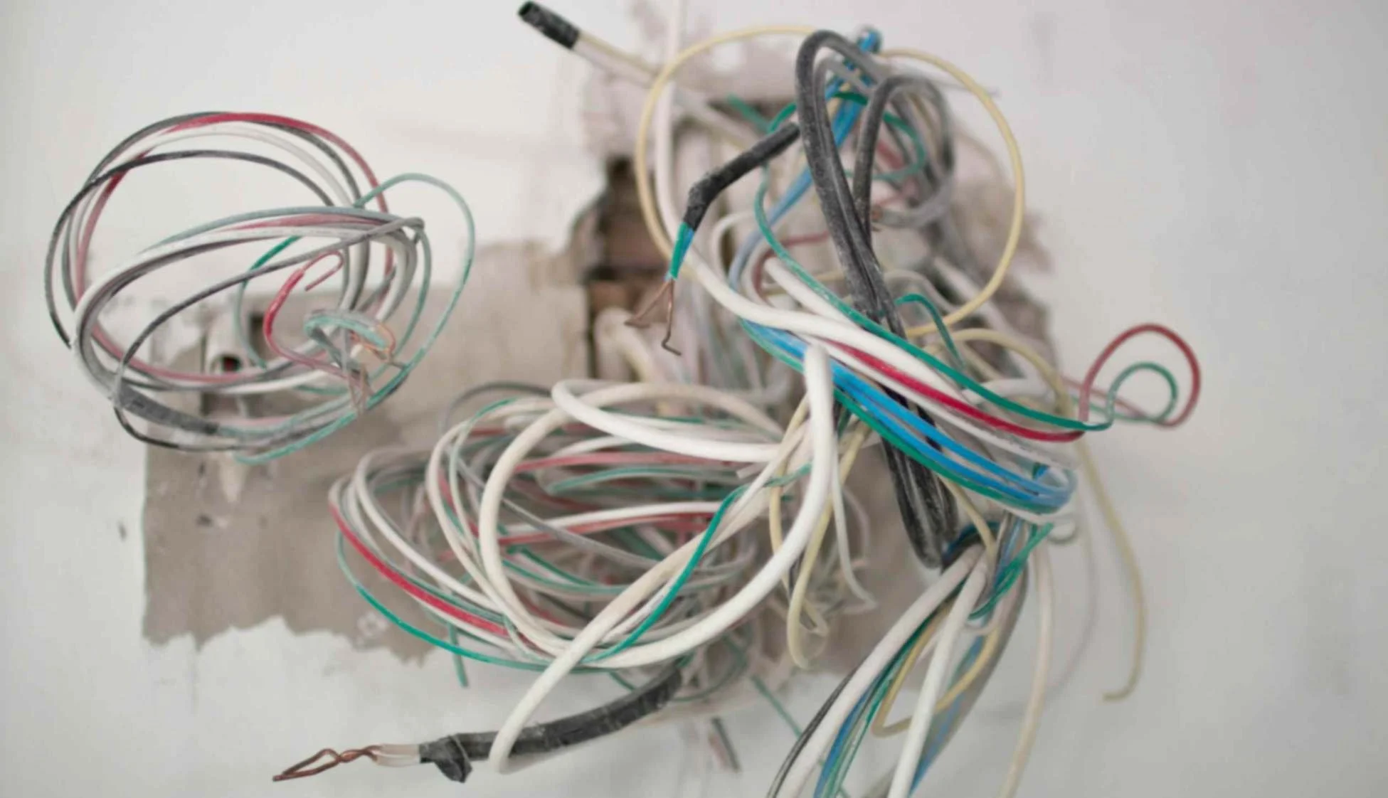 old outdated wiring of various colours coming out of wall