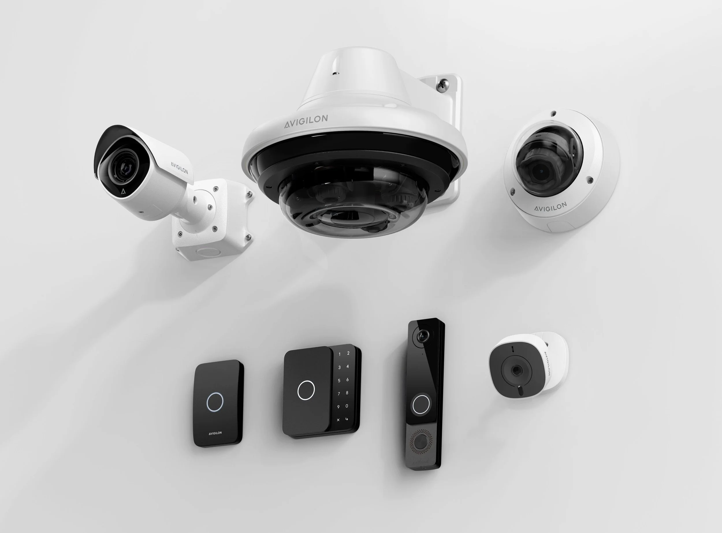 A collection of modern security and smart home devices, including security cameras, remote controls, and a keypad, all mounted on a white wall.
