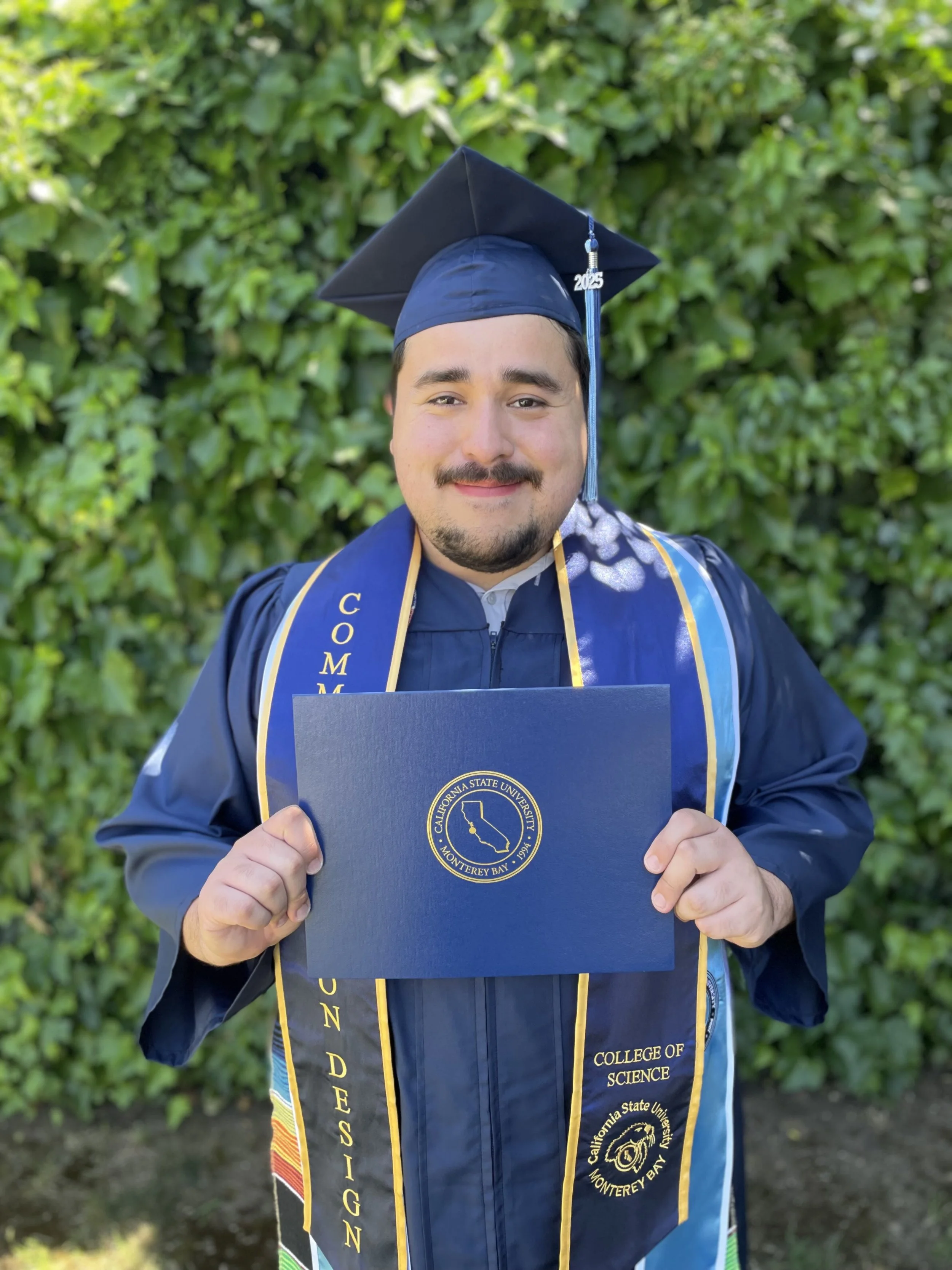 Brandon Cabrera in a graduation cap and gown holding his college degree.