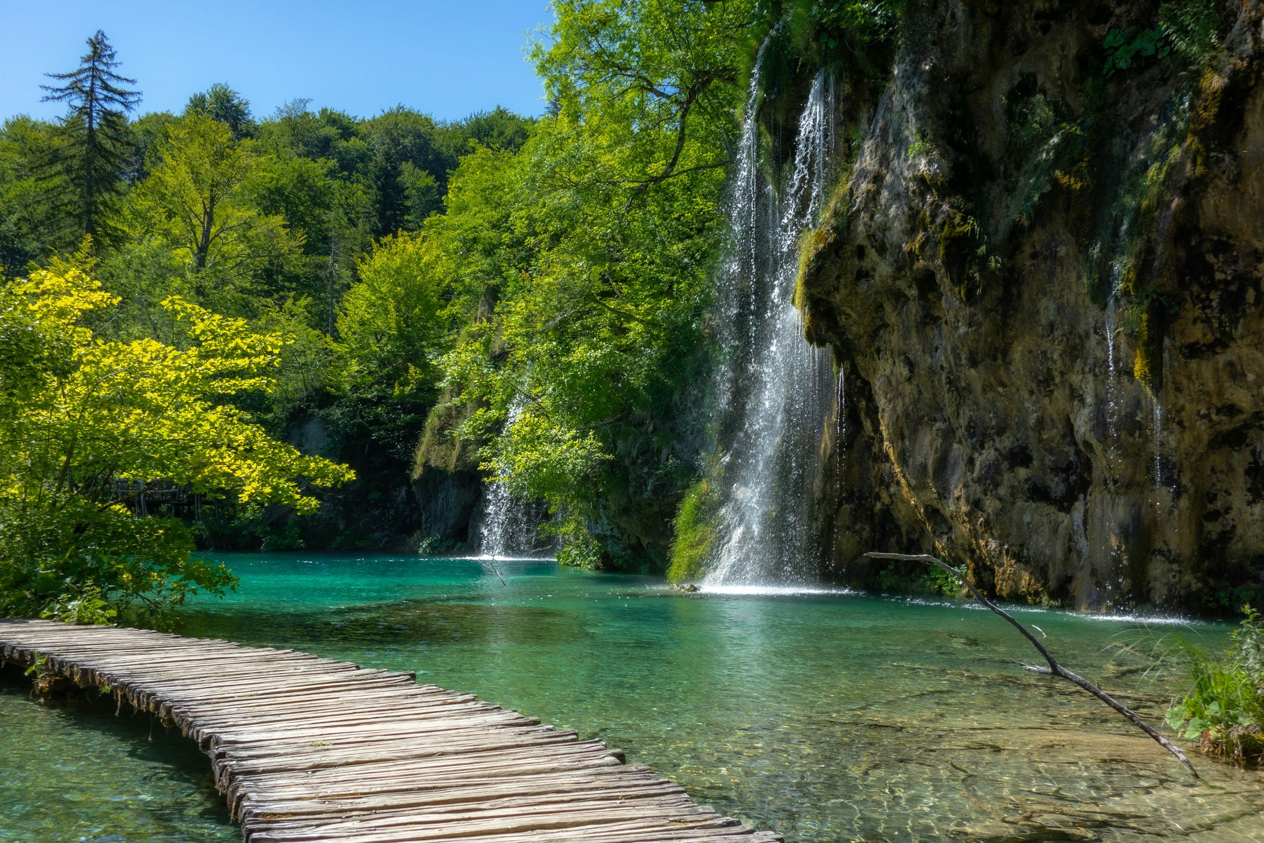 Waterfall in a lagoon with a wooden walkway next to it