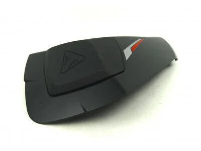 Svart plastkomponent med röd och vit dekorativ detalj, troligen en del av en motorcykel eller bil.