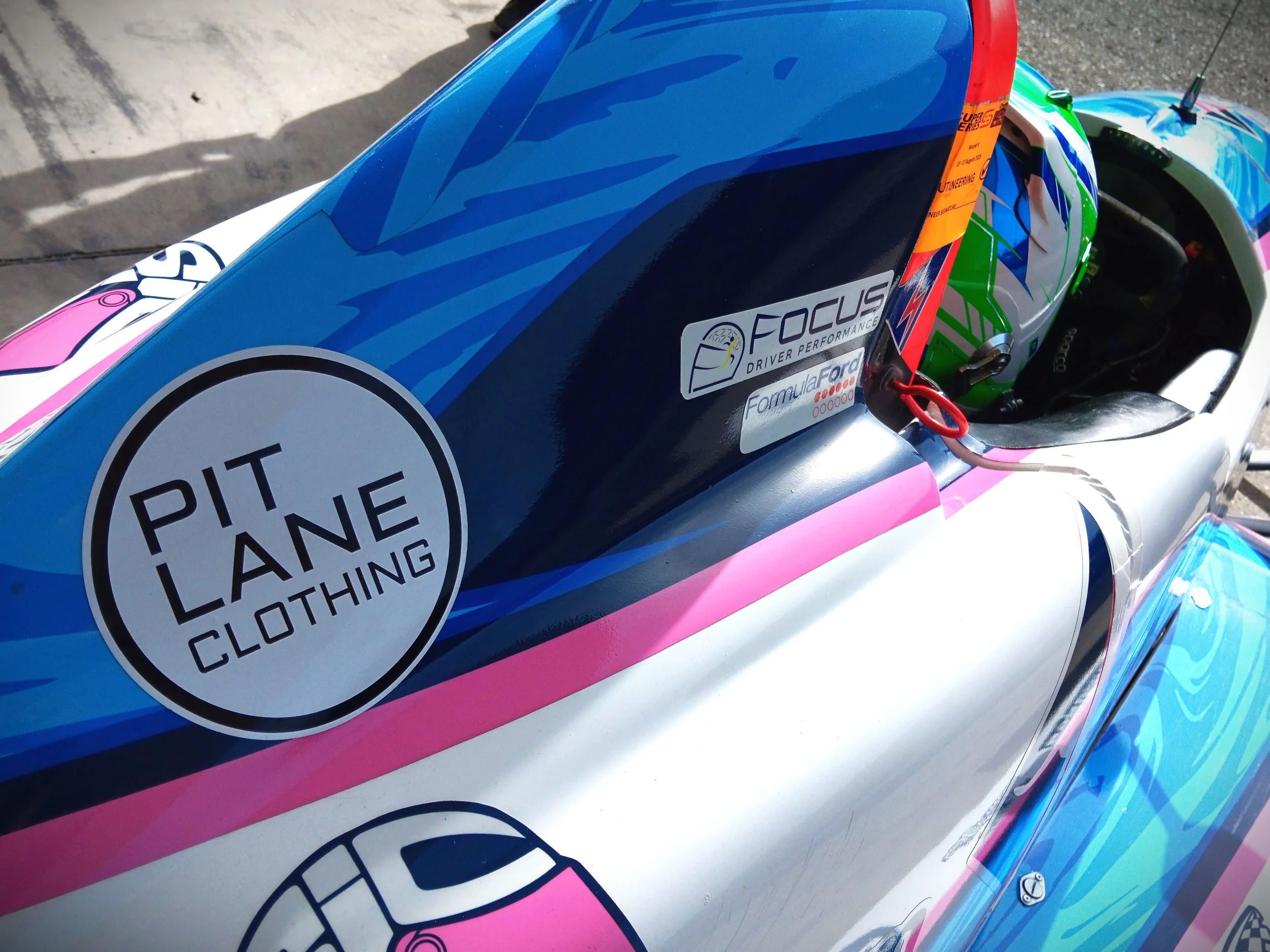 Race cars in various colors competing on a track, with drivers wearing helmets, during a motorsport event.