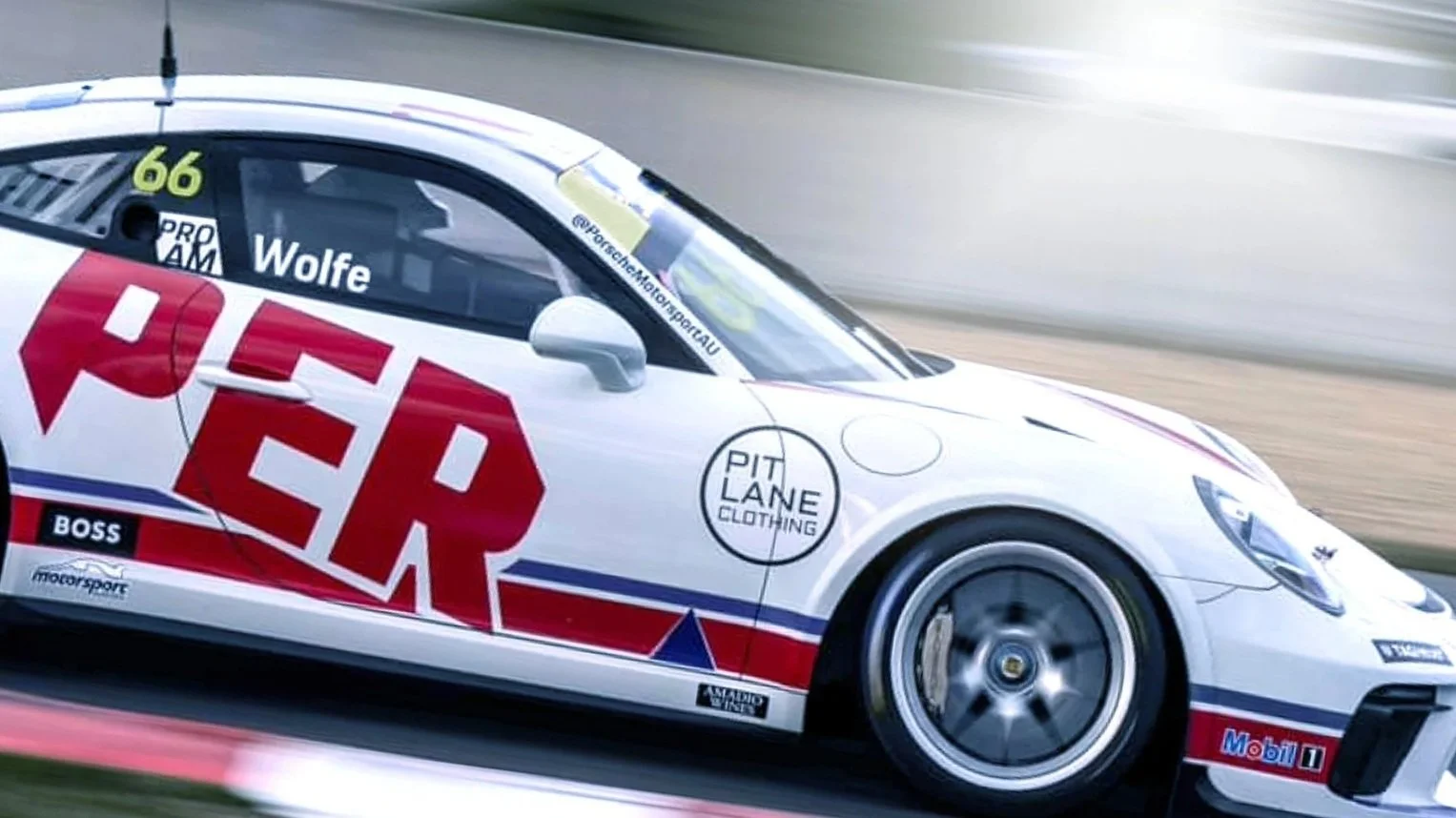 Side view of a white race car with red and blue decals, featuring logos including 'Pit Lane Clothing' and 'Wolfe', driving on a race track.