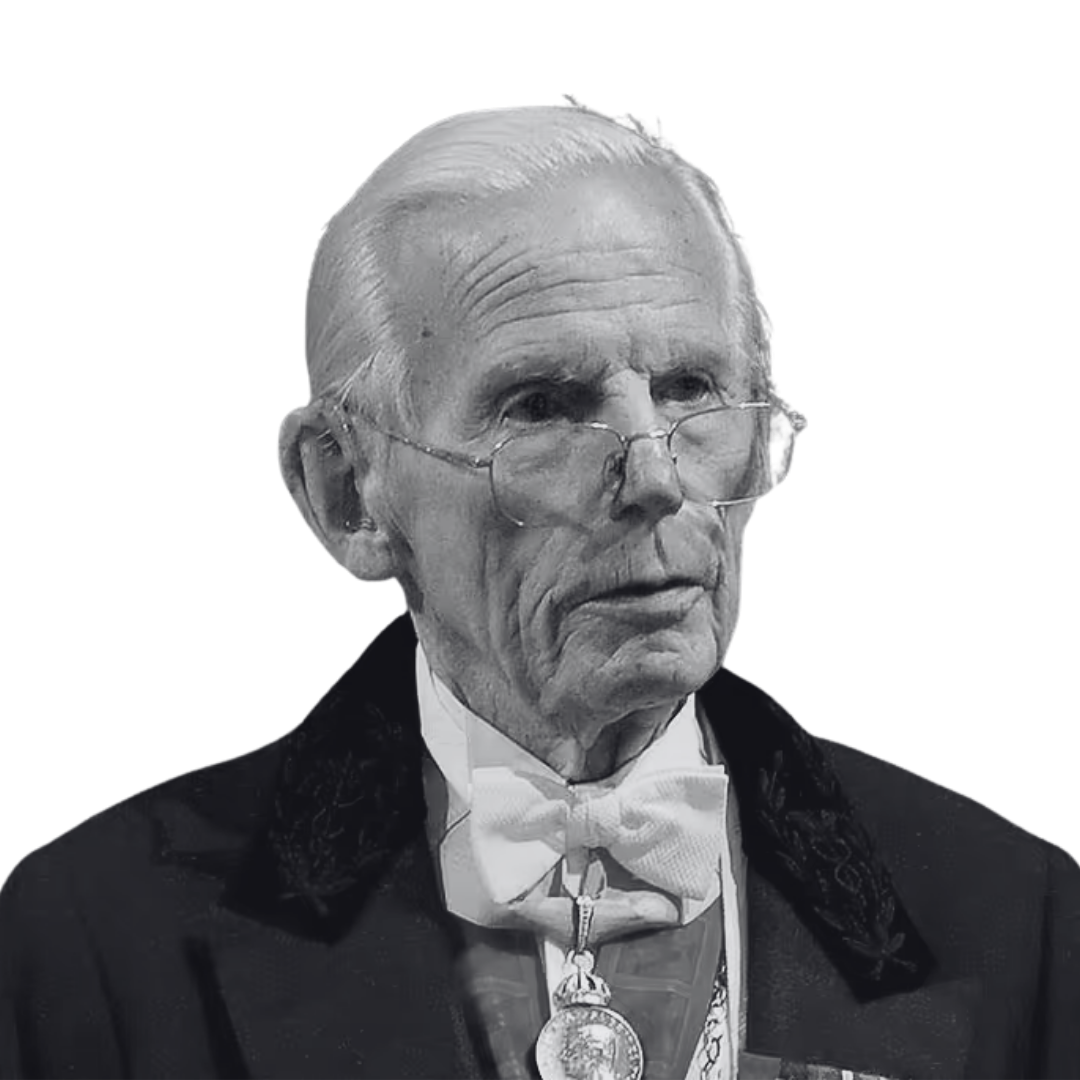 Black and white photo of an elderly man with white hair, glasses, wearing a tuxedo with a bowtie and a medal around his neck.