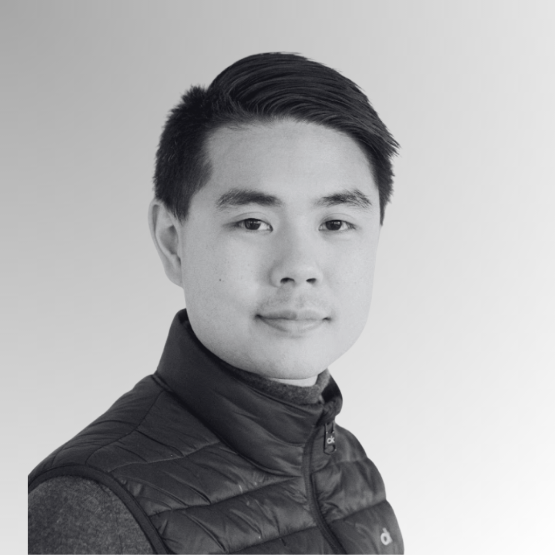Black-and-white portrait of a young Asian man with short, neatly styled hair, wearing a zip-up jacket with a high collar and a knit sweater underneath.