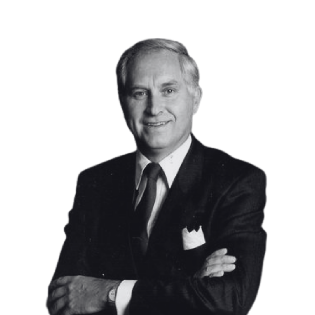 Black and white portrait of a man wearing a suit and tie, with hair combed back, smiling and crossing his arms.