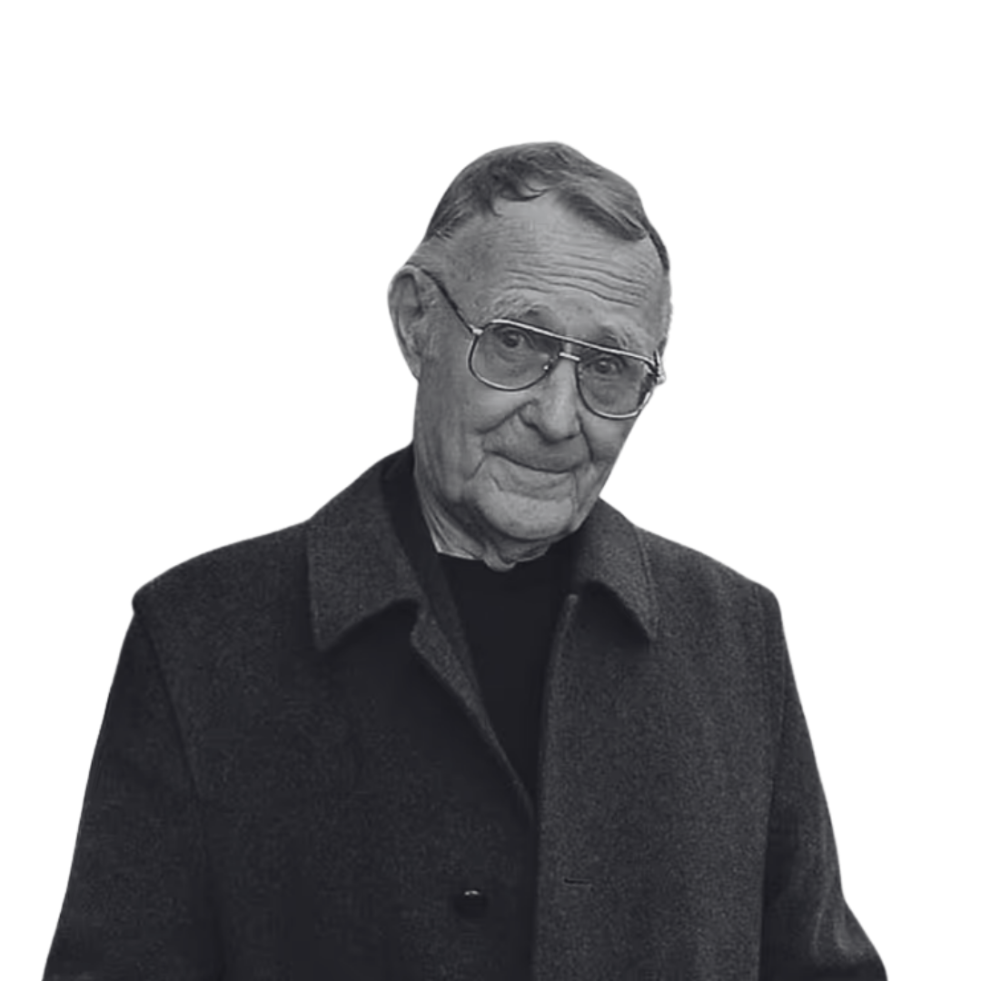 Black and white photo of an elderly man wearing glasses, a dark coat, and a collared shirt, looking at the camera with a slight smile.