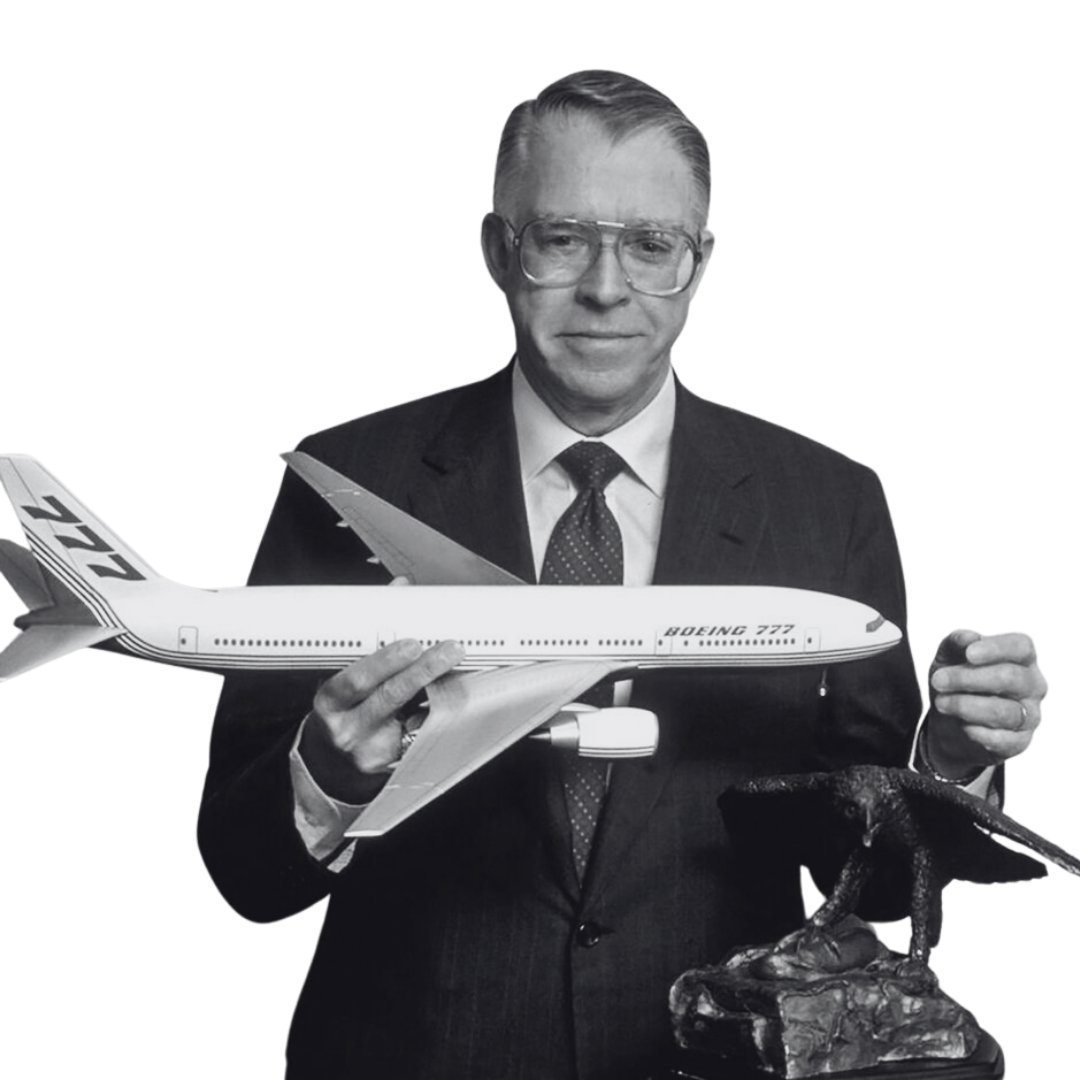 A black and white photo of a man in a suit and tie holding a model airplane and a bird sculpture.