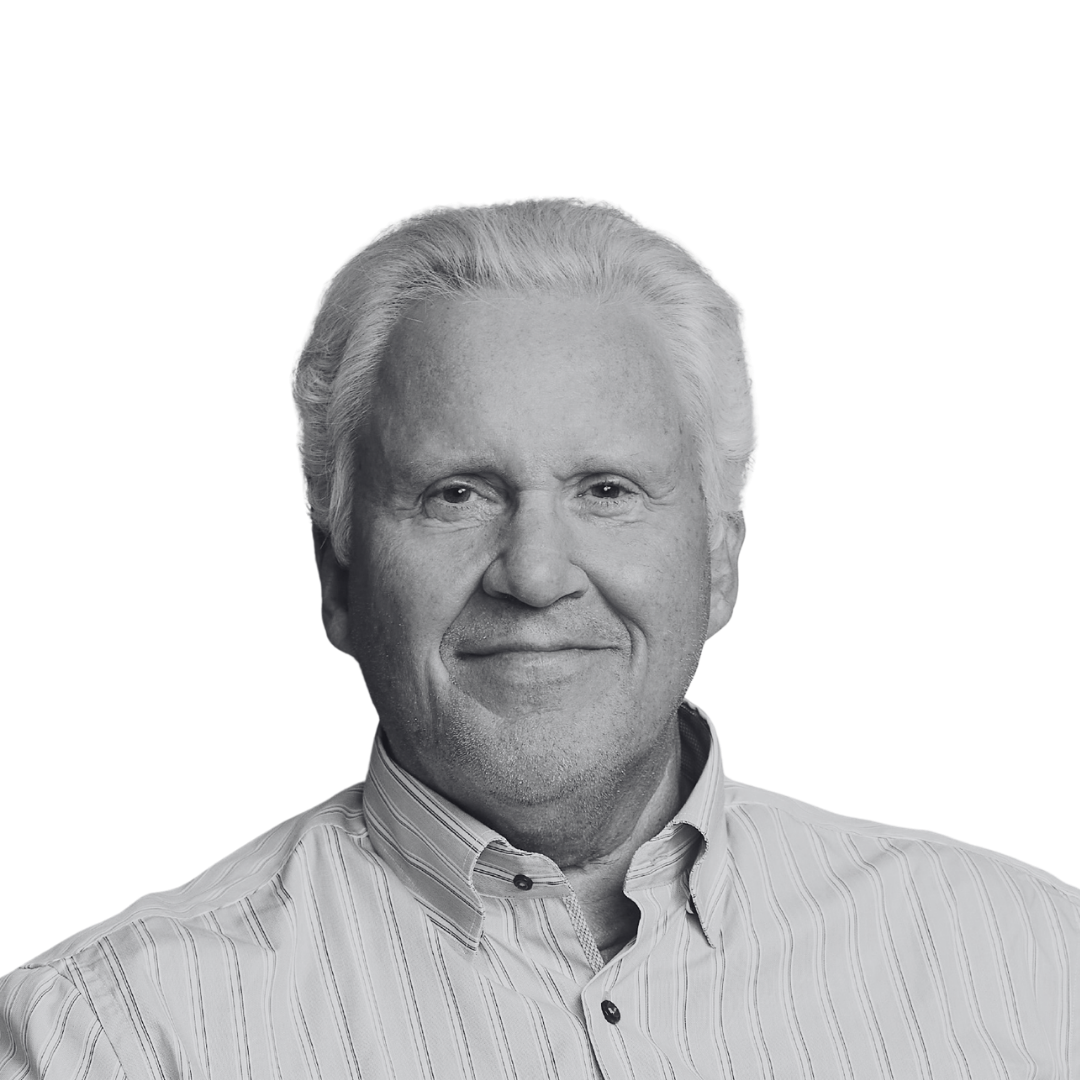 A black and white portrait of an older man with gray hair, wearing a light-colored, striped button-up shirt, smiling gently.