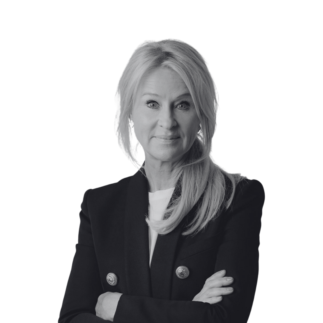 Black and white portrait of a middle-aged woman with light hair, wearing a blazer with two buttons and a white shirt underneath, crossing her arms and looking at the camera.