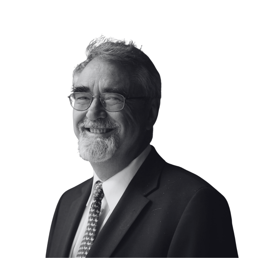 Black and white portrait of a smiling man with glasses, a beard, and wearing a suit and patterned tie.