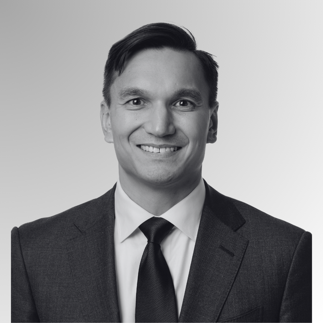 Black and white close-up portrait of a smiling man wearing a suit.