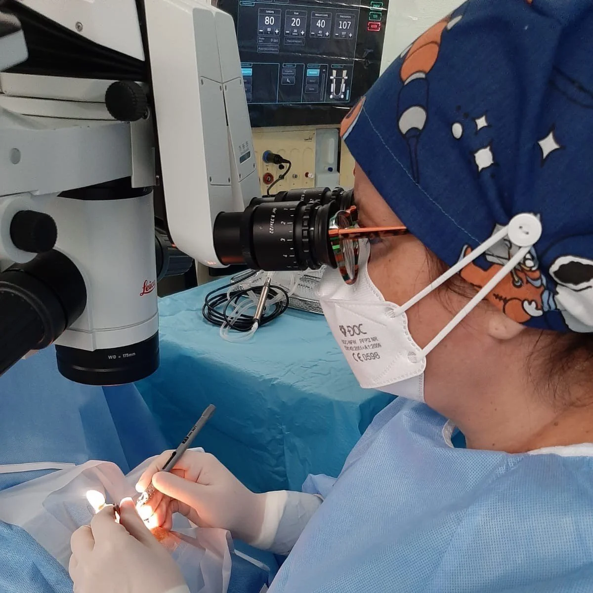 Chirurg bei einer Operation, schaut durch ein Mikroskop.