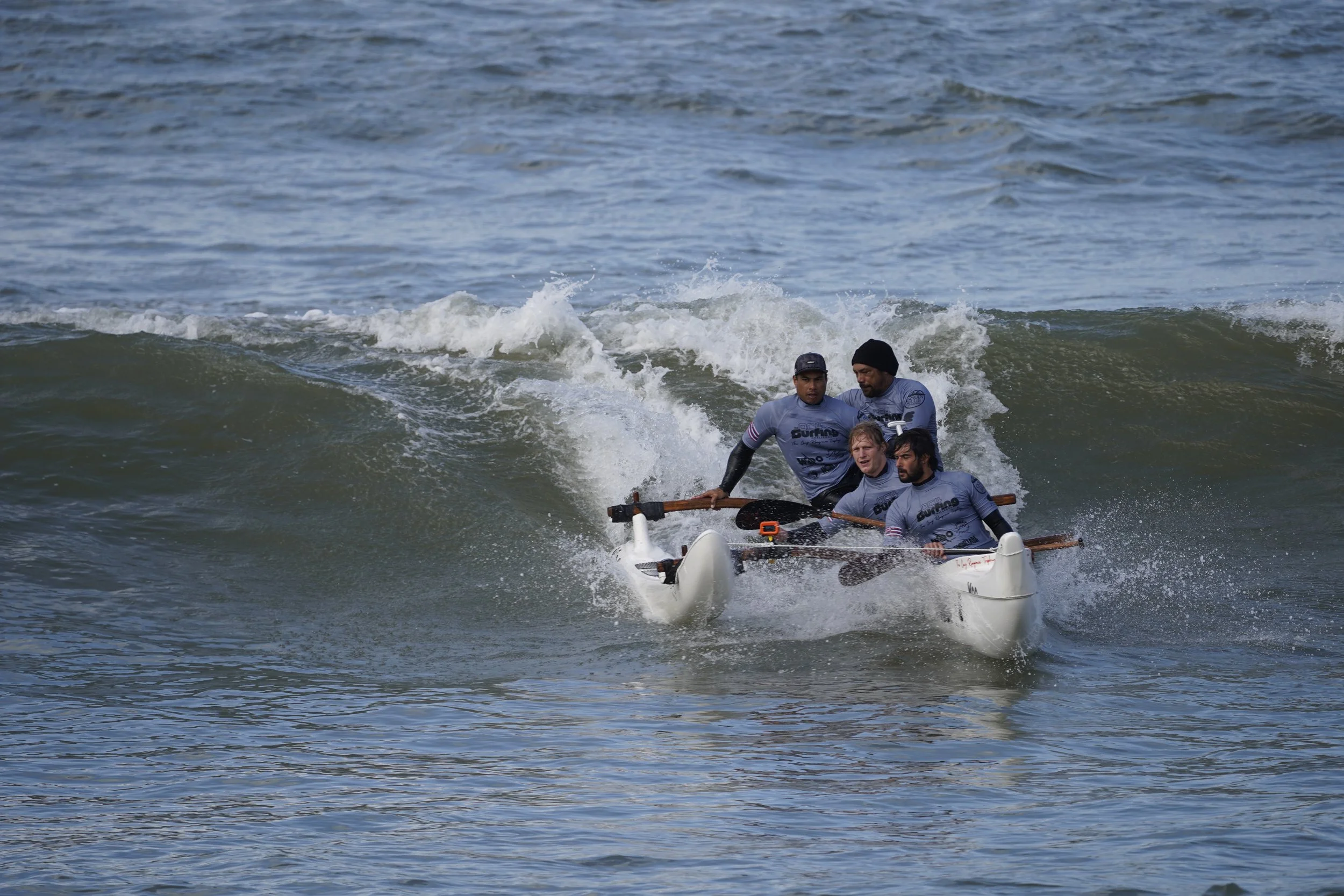 équipage de pirogue hawaïenne OC4 surf en train de prendre une vague en compétition