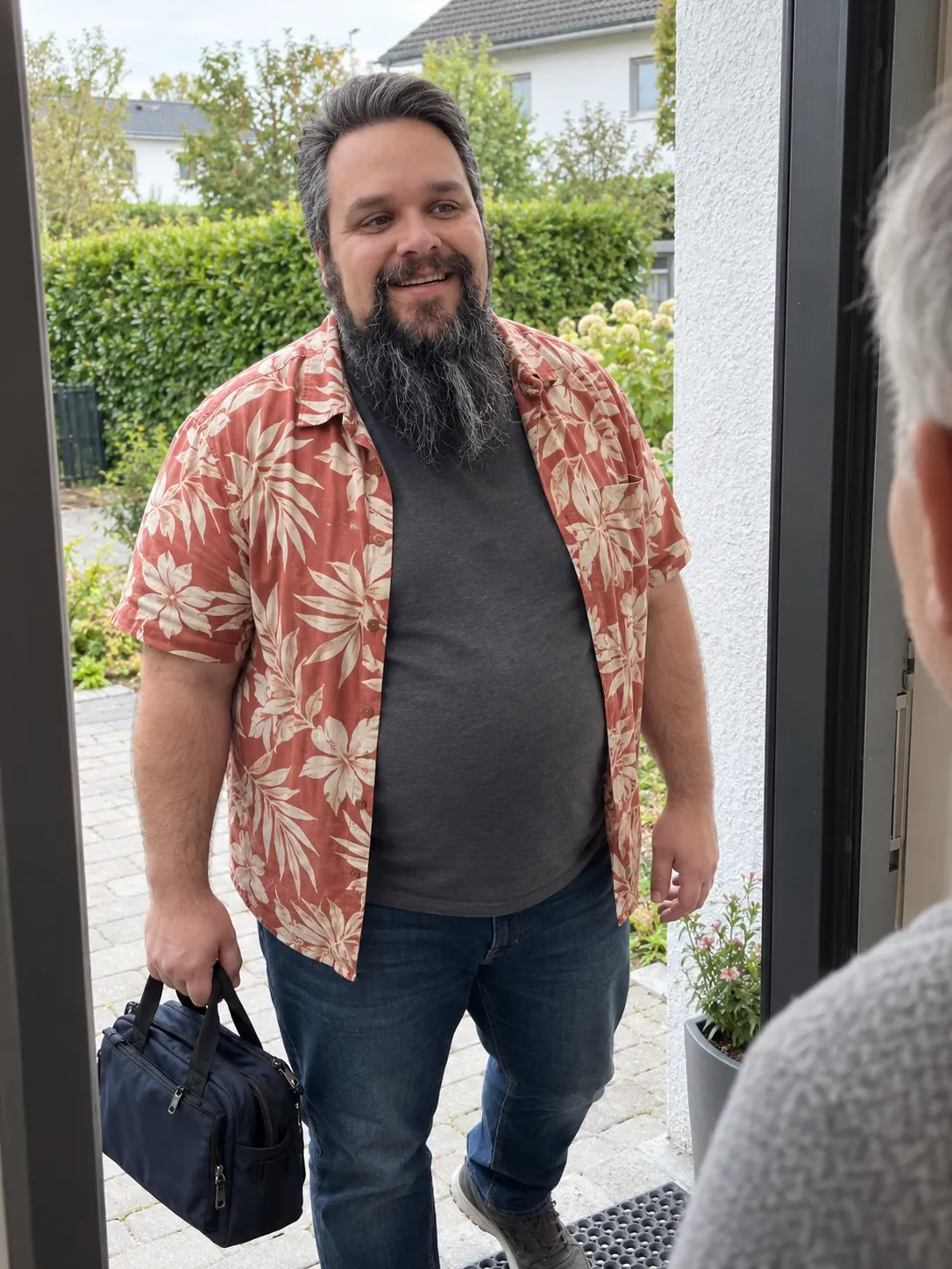Alexander Klein von TechniKing begrüßt einen Kunden an der Haustür und trägt seine Techniktasche zum Hausbesuch.