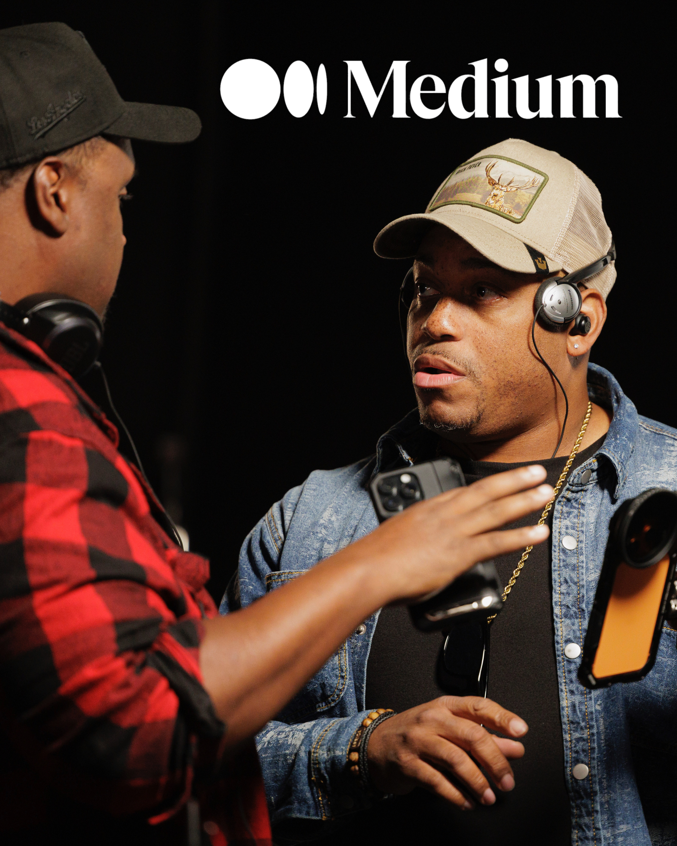 Two people with headphones having a conversation, one wearing a cap with a deer patch, the other in a denim jacket and a beige cap, against a black background with the words 'Medium' and a logo.