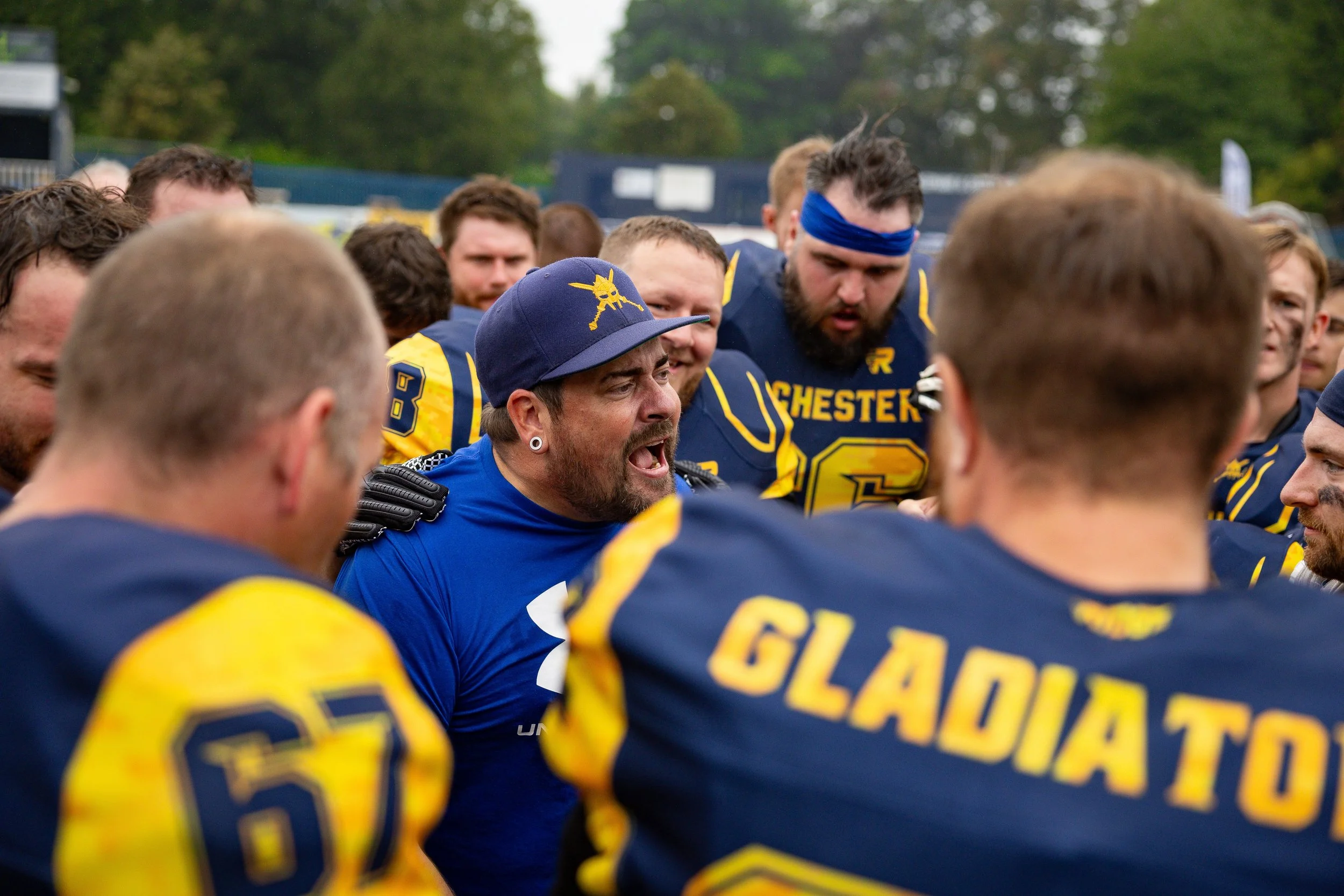 American football team huddled together on the field, with one player visibly shouting during a game.