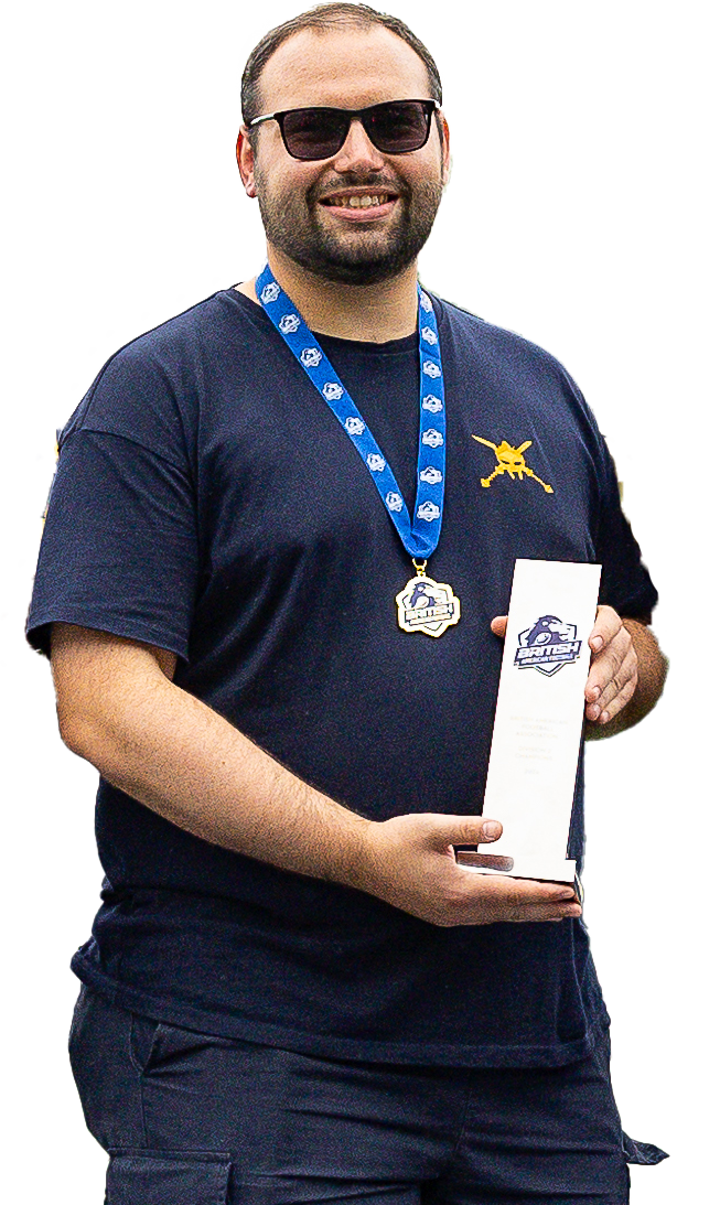 Man with sunglasses wearing a navy T-shirt with a logo, holding a trophy, and wearing a medal around his neck with a blue ribbon.