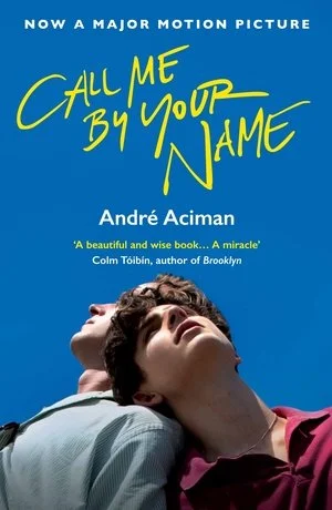 Book cover for 'Call Me By Your Name' by André Aciman, featuring two young men looking upward with a blue background.主题诠释the book's romantic and introspective nature.