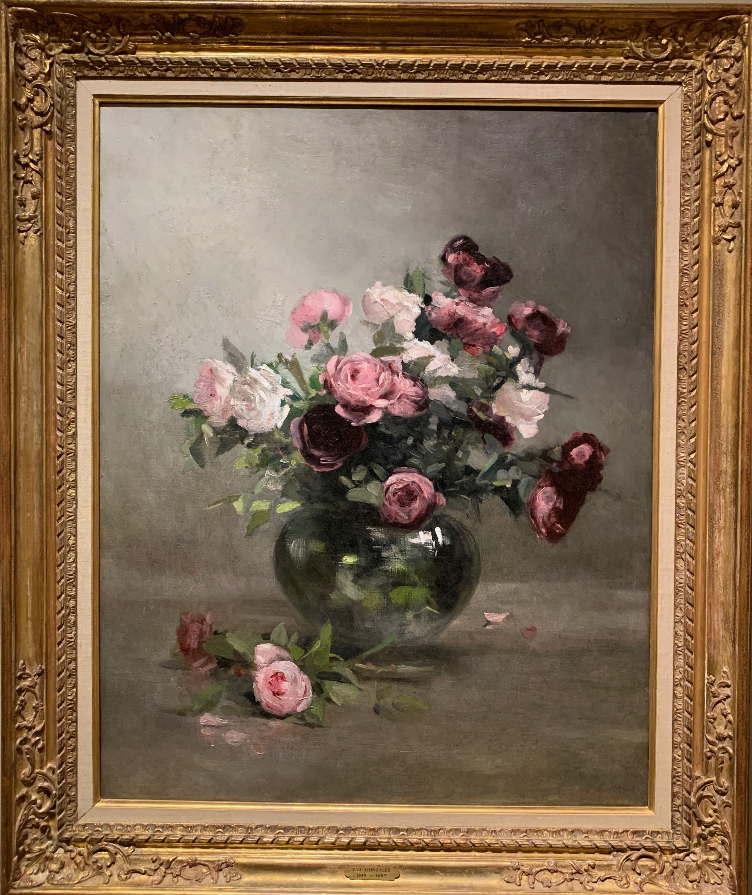 Painting of a bouquet of pink and white roses in a dark vase, with some flowers and leaves fallen on the surface beside it.