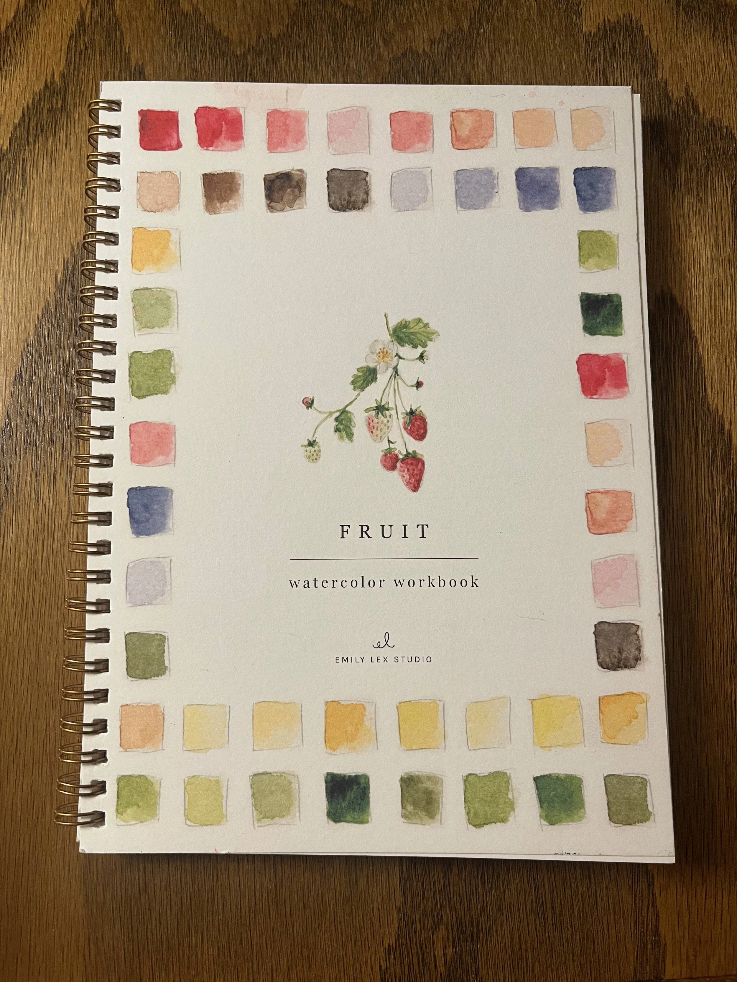 Watercolor workbook titled 'Fruit' by Emily Lex Studio, featuring a strawberry plant illustration on the cover, with colorful watercolor swatches border.