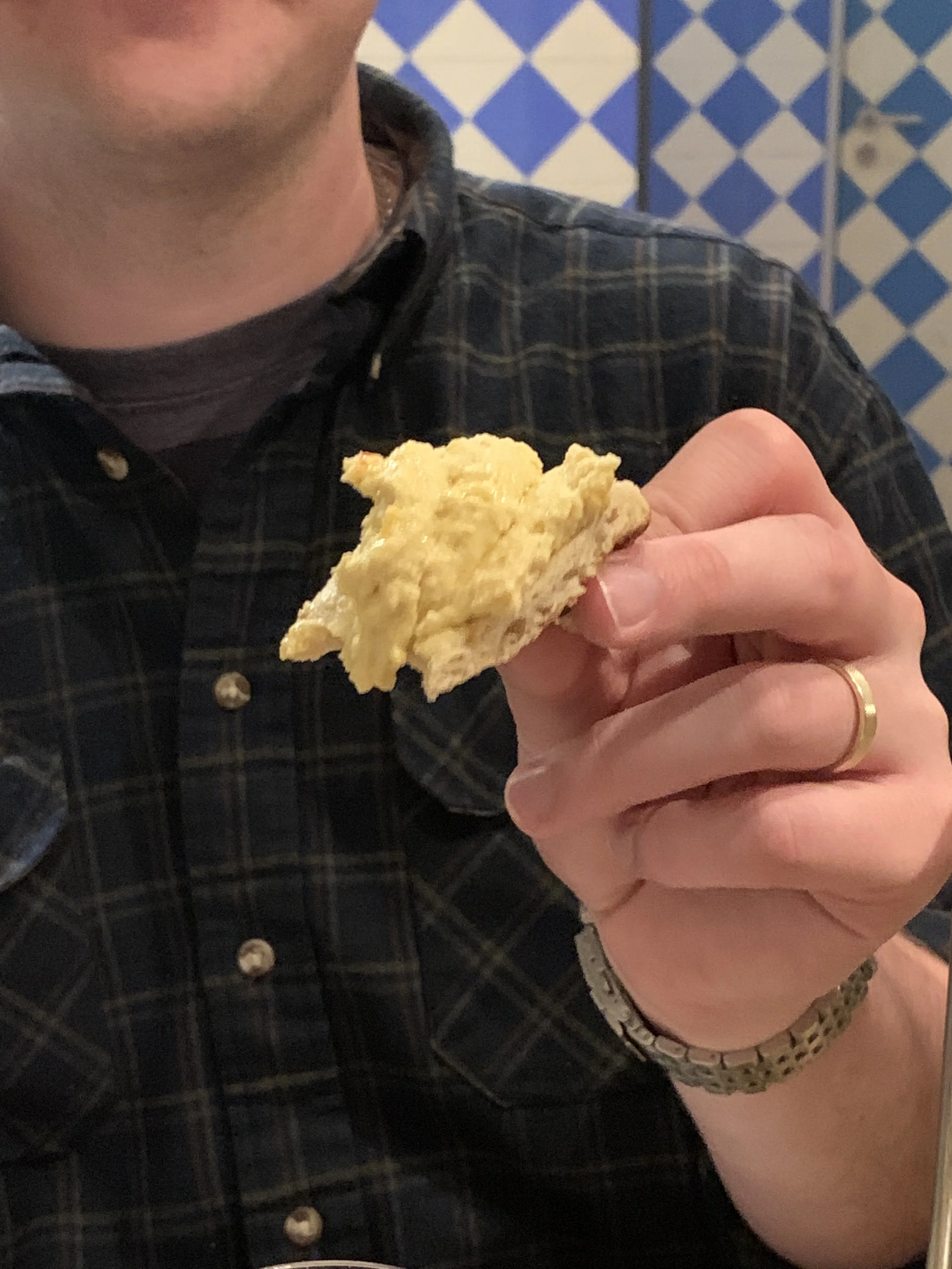 Person holding a piece of pie in front of a blue and white checkered background.