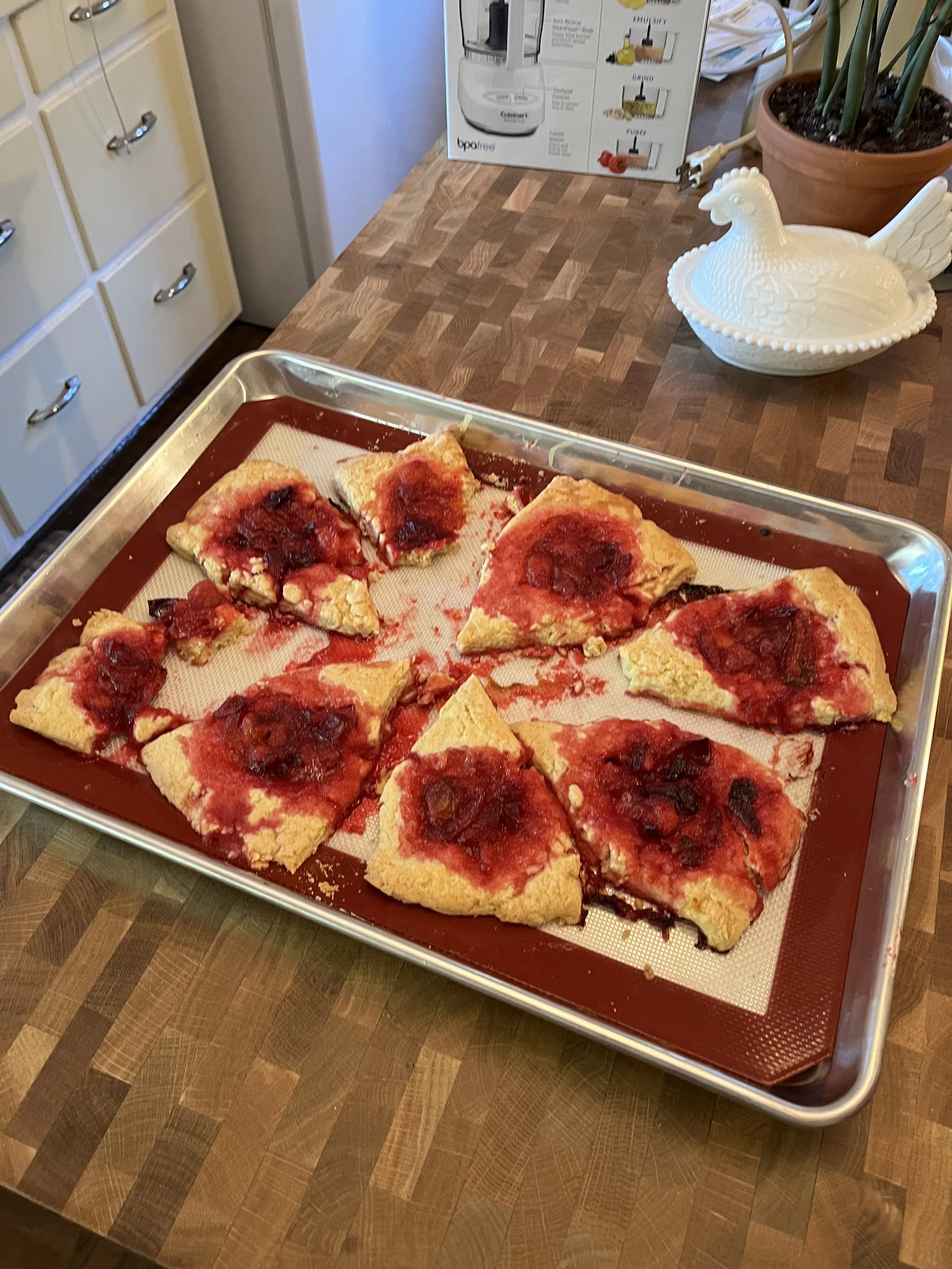 Slices of strawberry pizza on a baking sheet in a kitchen.
