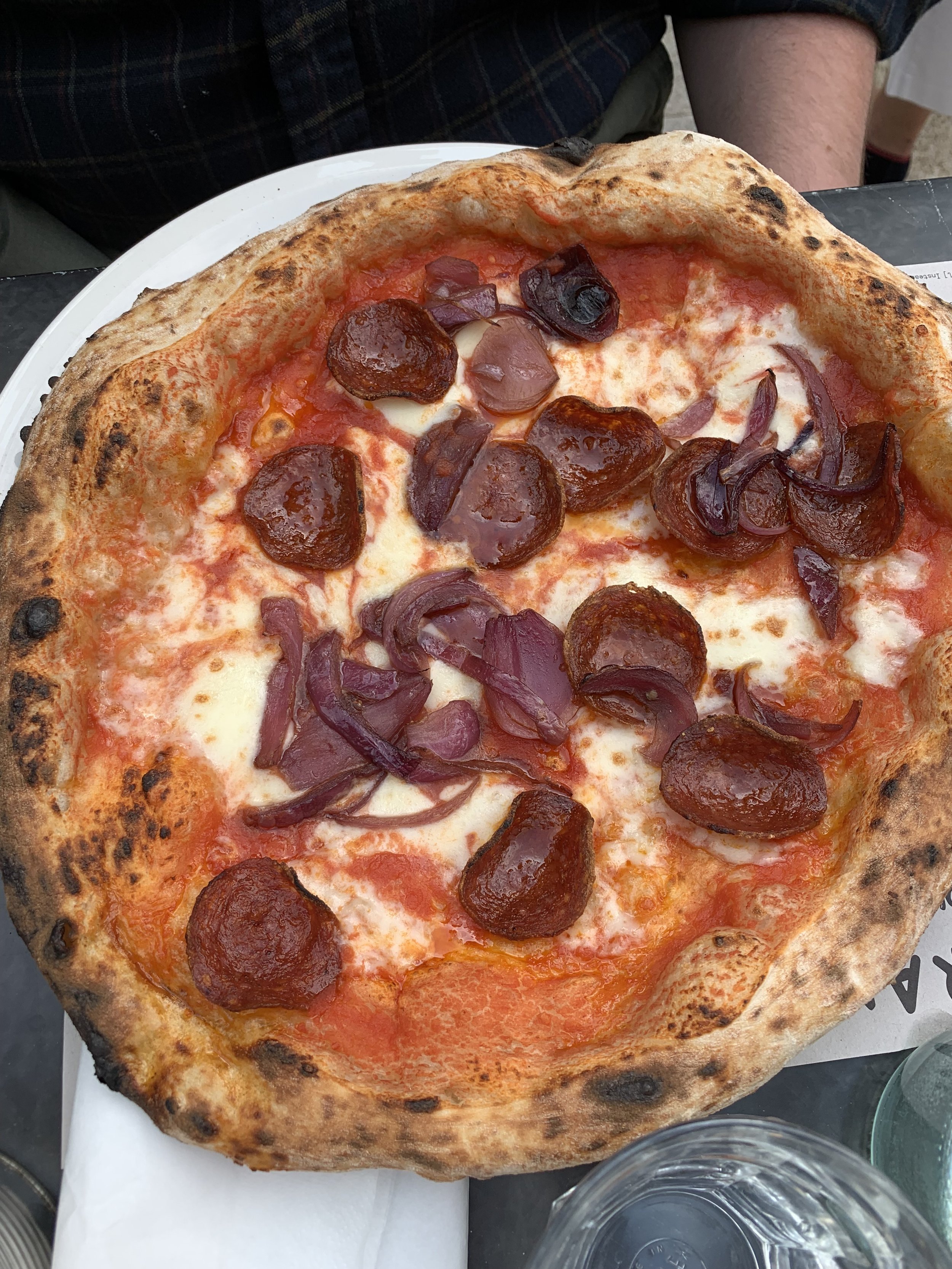 A pizza with pepperoni slices and caramelized onions on a thin crust.